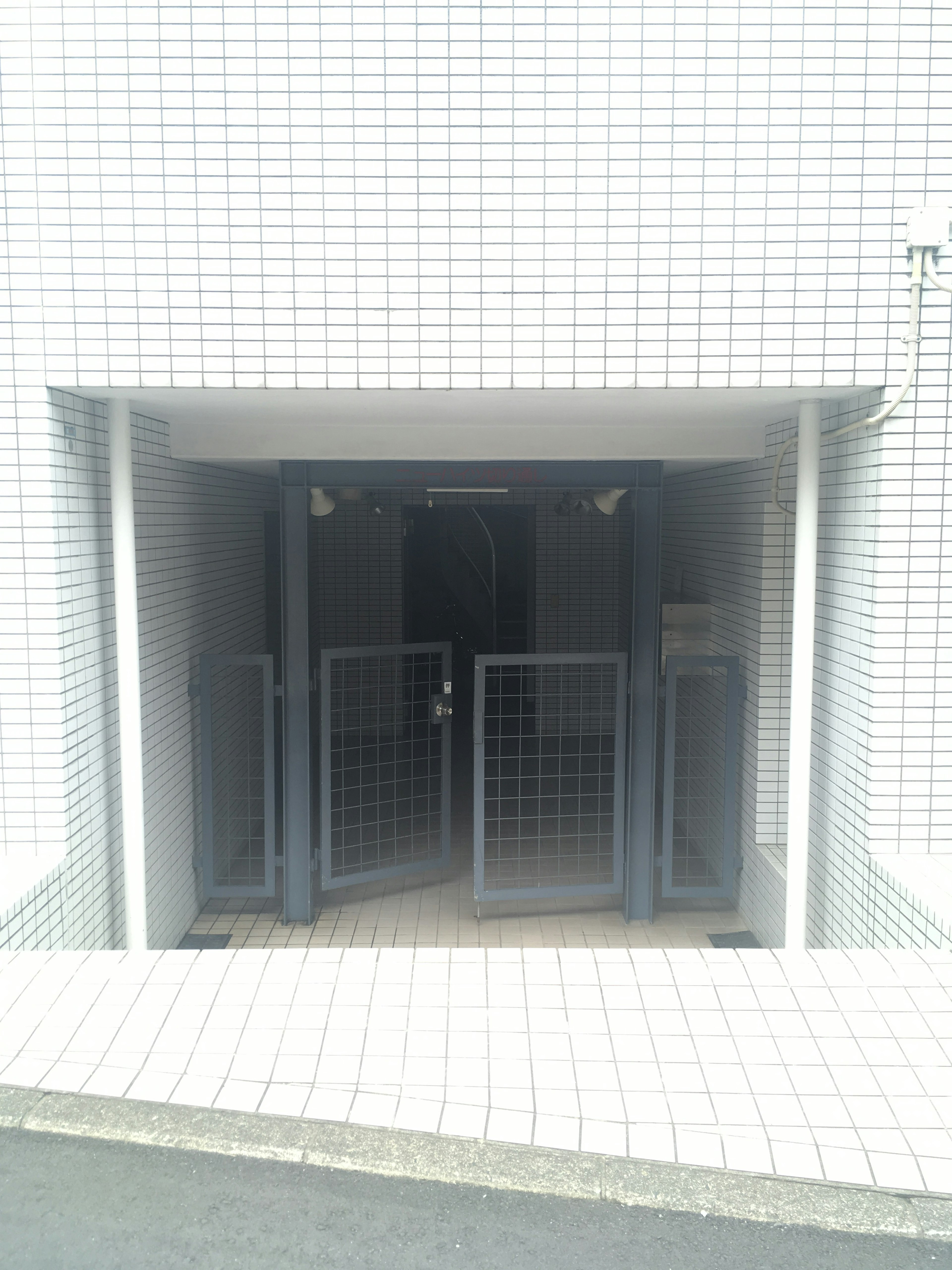 Entrance with metal gates surrounded by white tiled walls