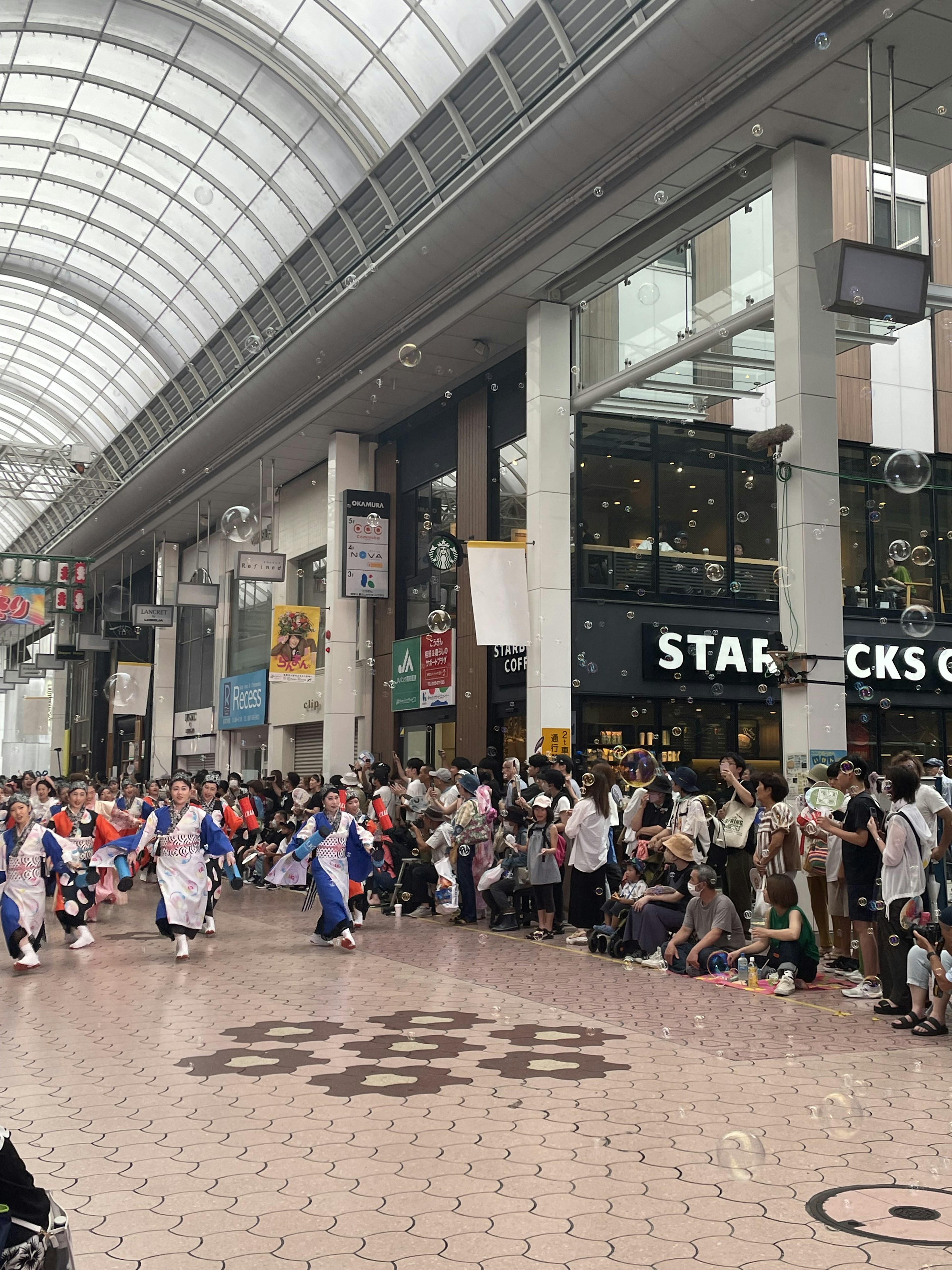 Área comercial interior con un desfile de personas reunidas cartel de Starbucks visible