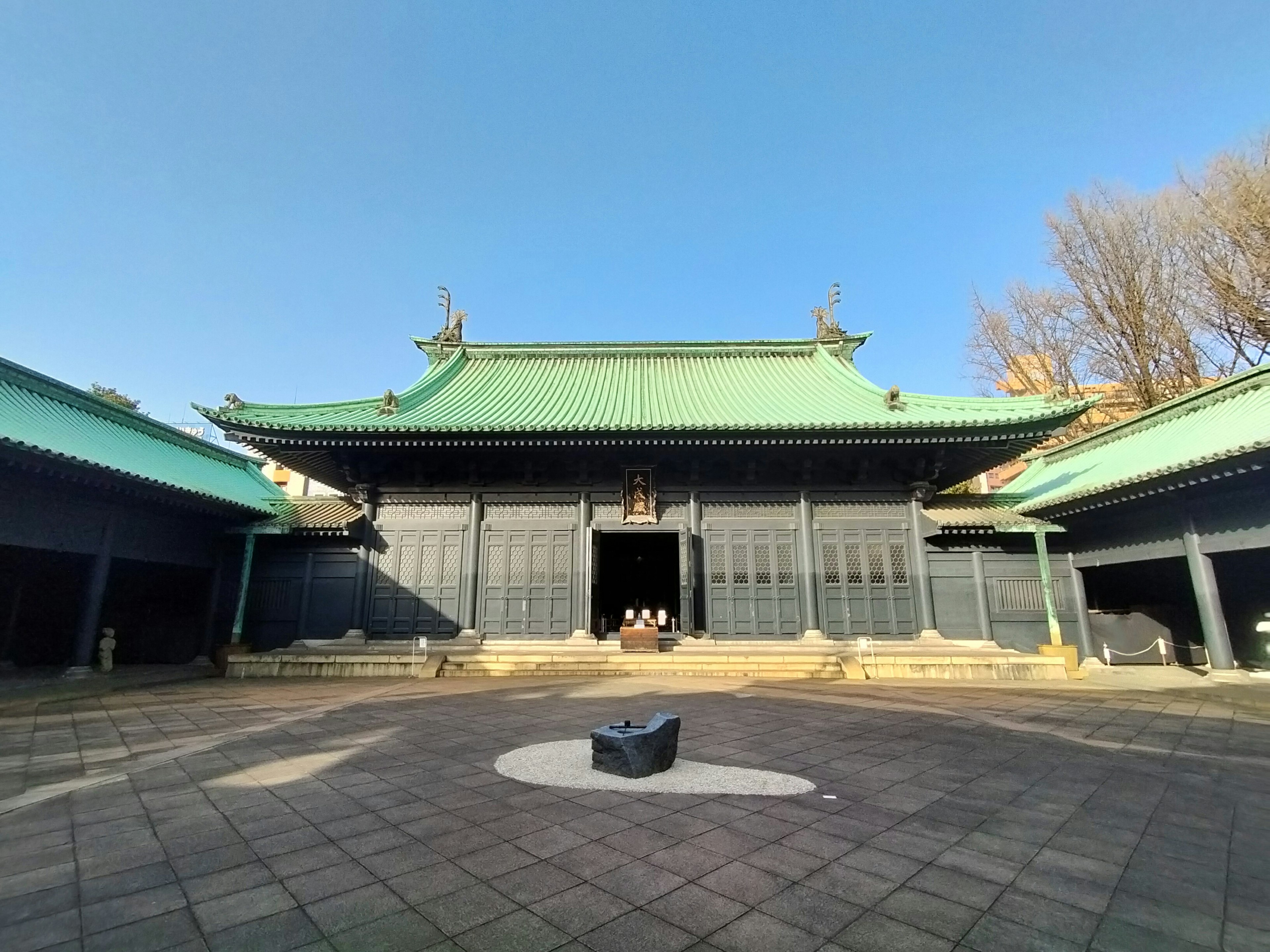 Bâtiment traditionnel avec un toit vert dans une cour spacieuse