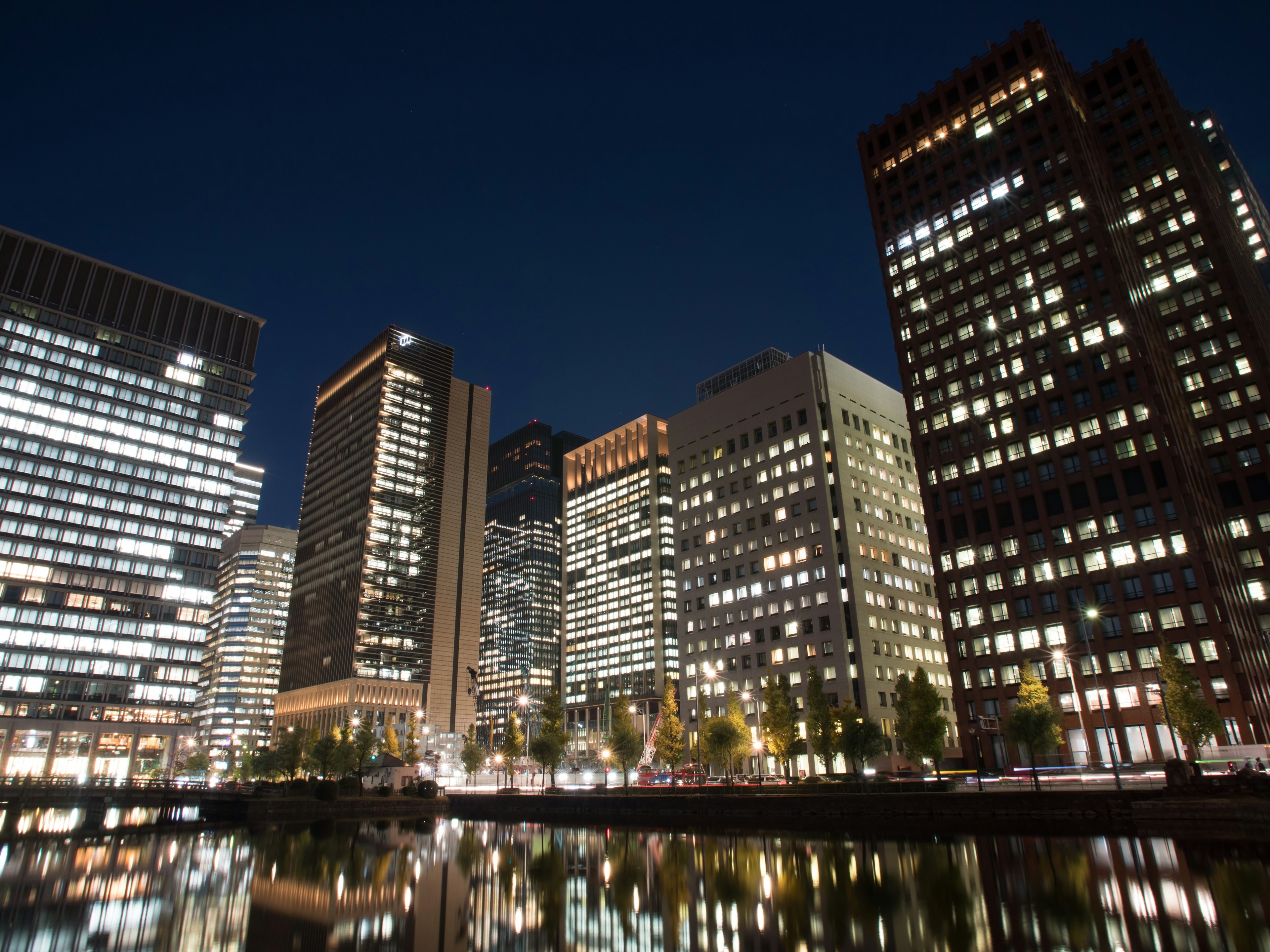 Paesaggio urbano notturno con edifici luminosi e riflessi sull'acqua