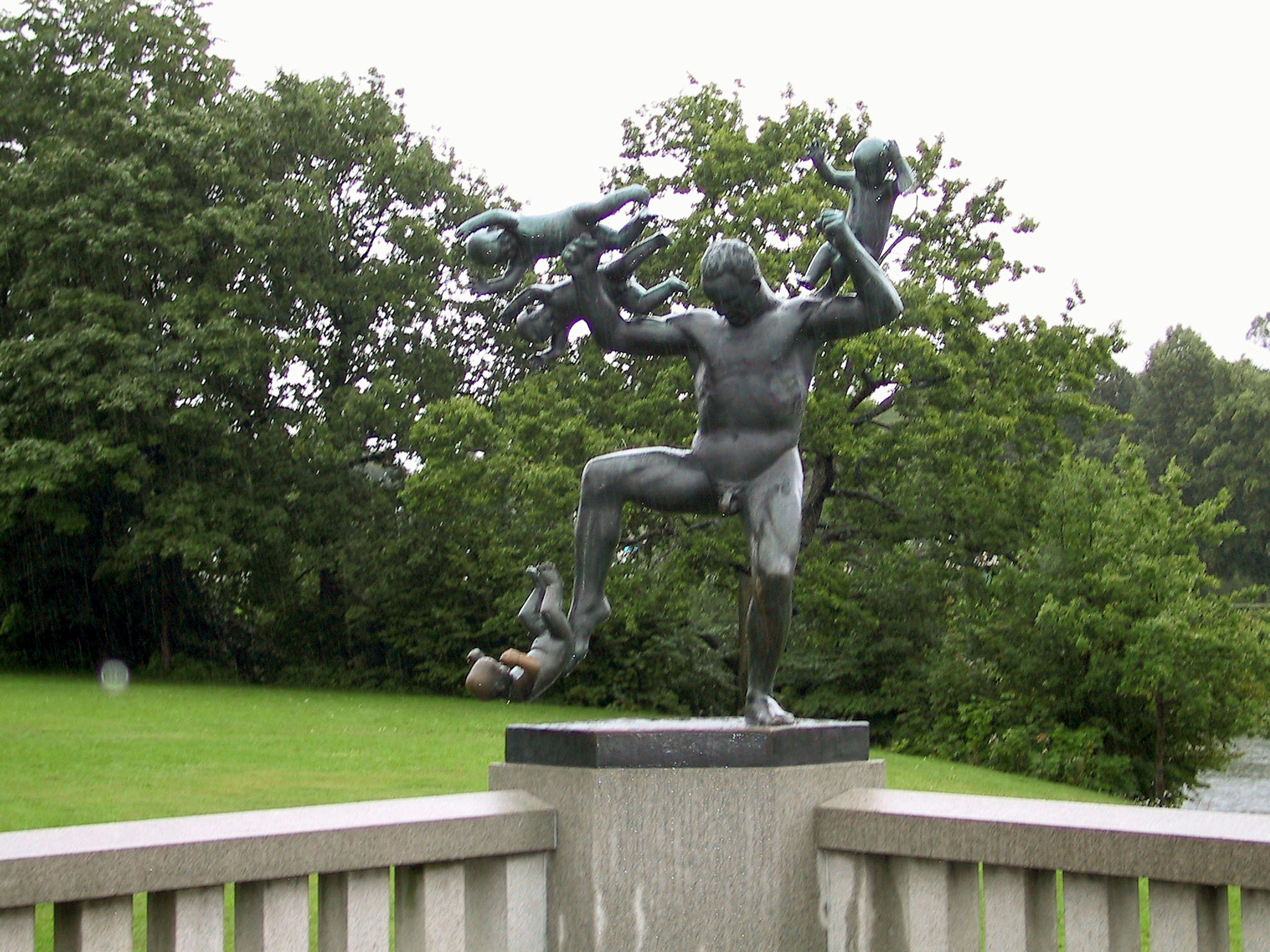 Sculpture en bronze d'un homme tenant des enfants dans les airs sur fond vert