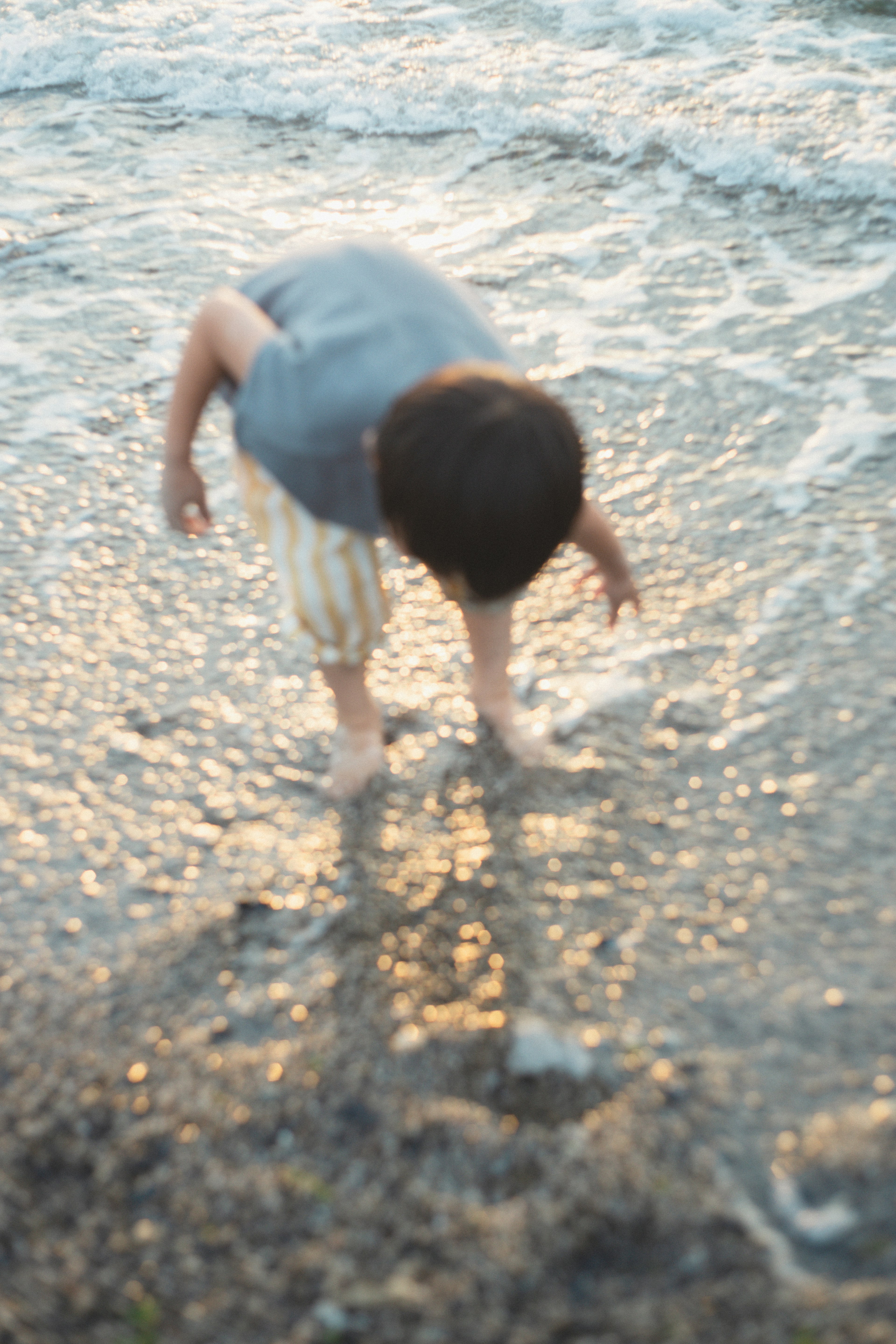 เด็กเล่นอยู่ที่ชายหาด ยื่นมือไปในน้ำ