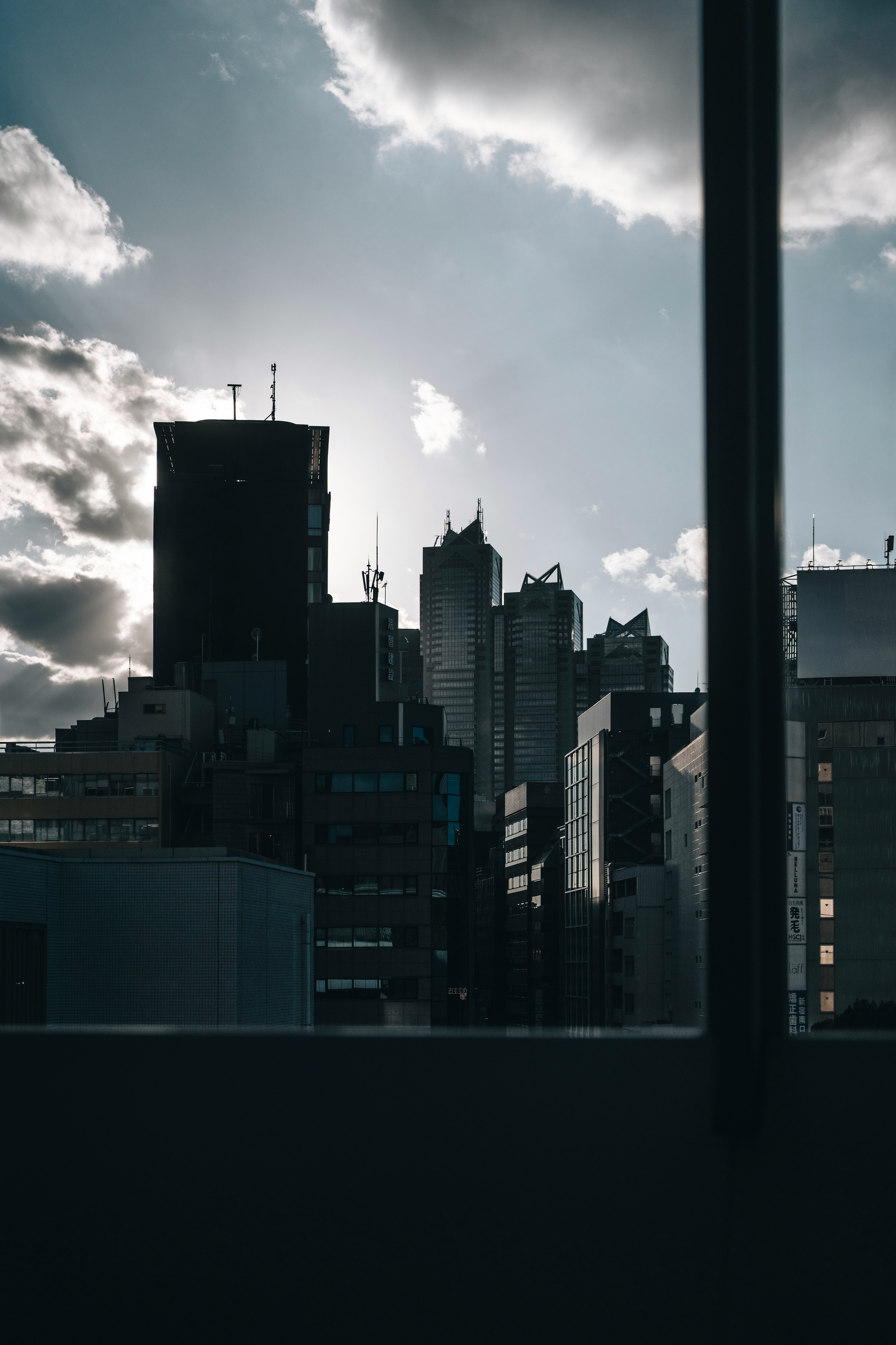 Silhouette di uno skyline cittadino vista attraverso una finestra con cielo nuvoloso