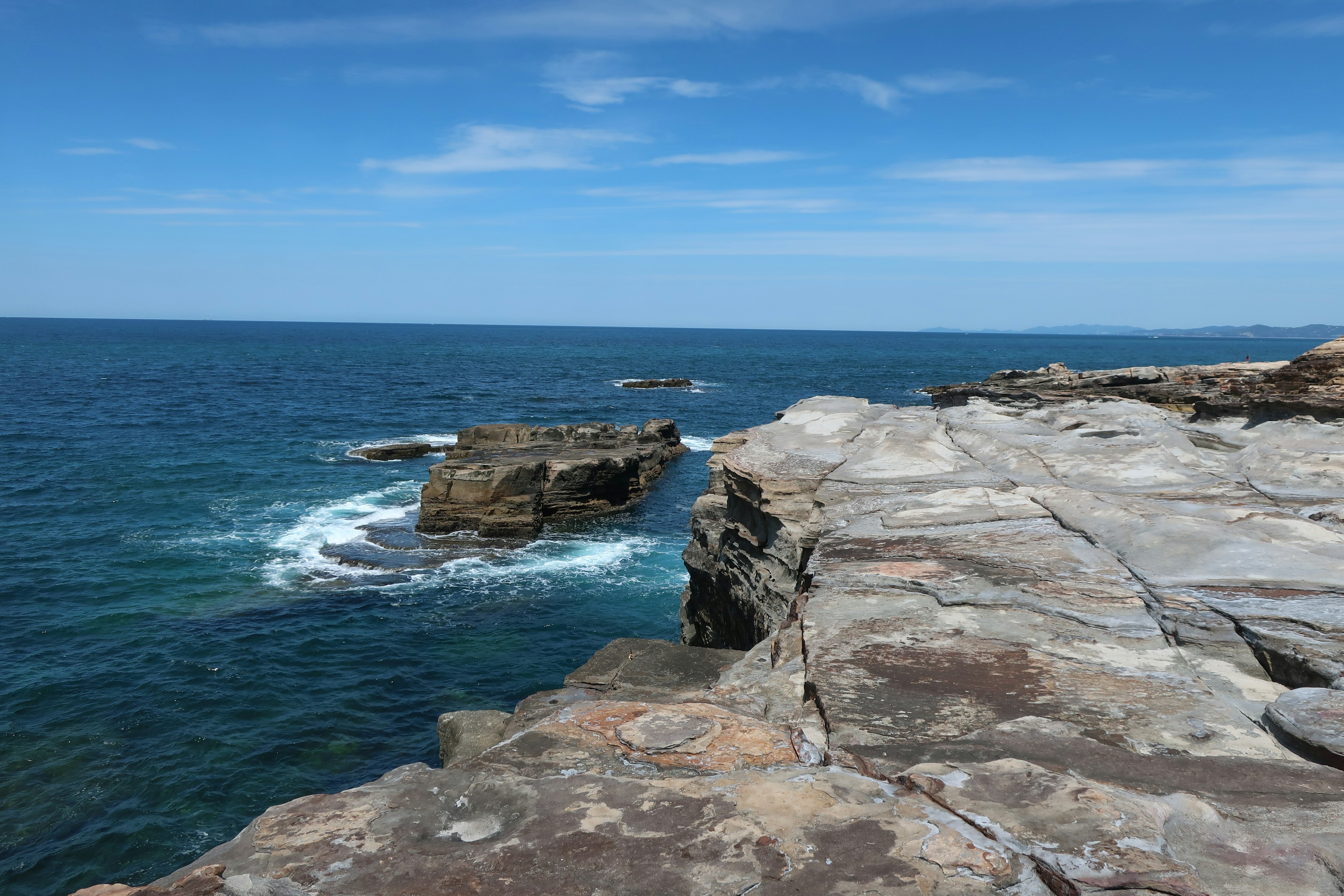 Rocky cliff overlooking the ocean under a clear blue sky