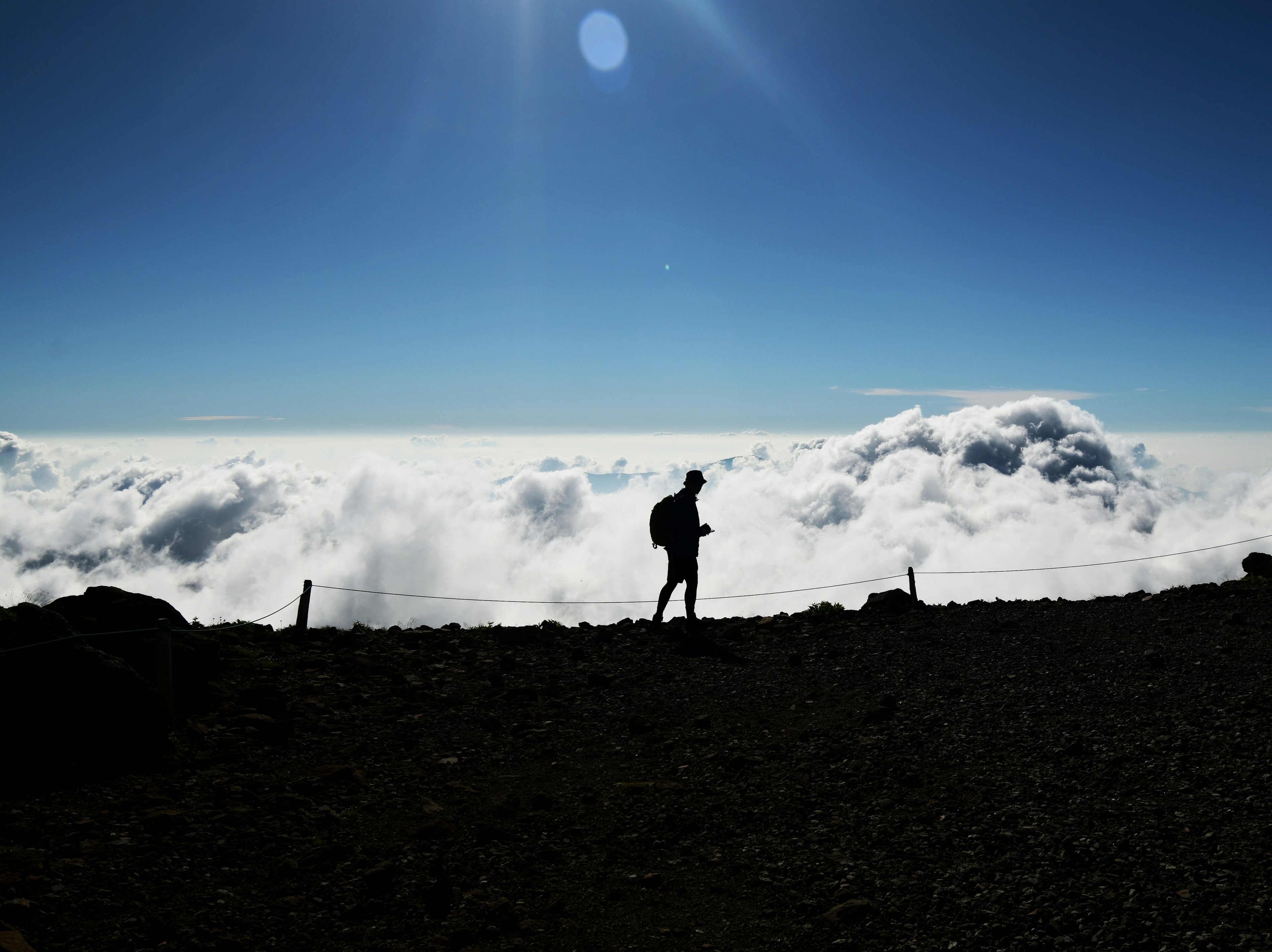 Silhouette einer Person, die über den Wolken mit klarem blauen Himmel geht