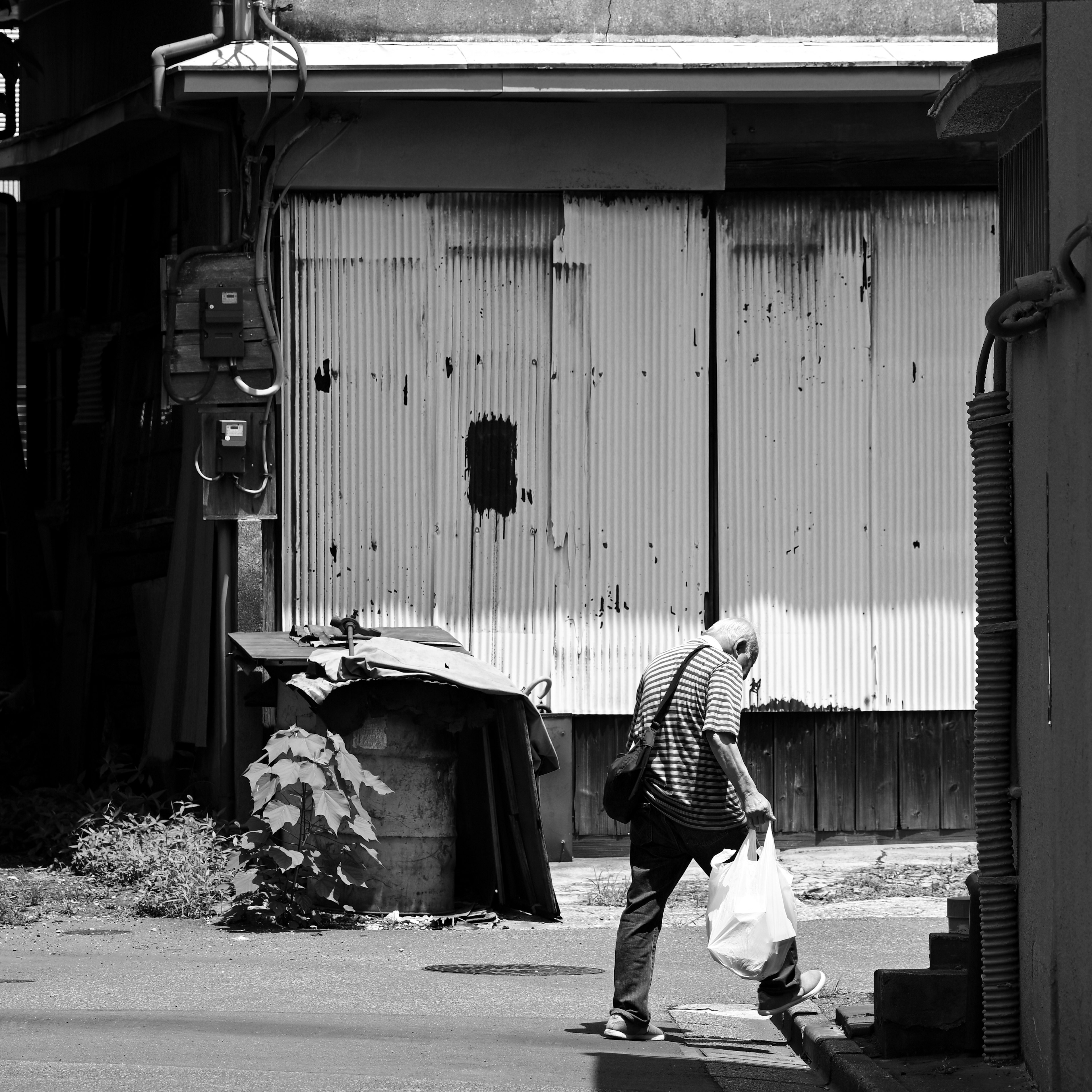 Un hombre mayor caminando con una bolsa en un entorno en blanco y negro