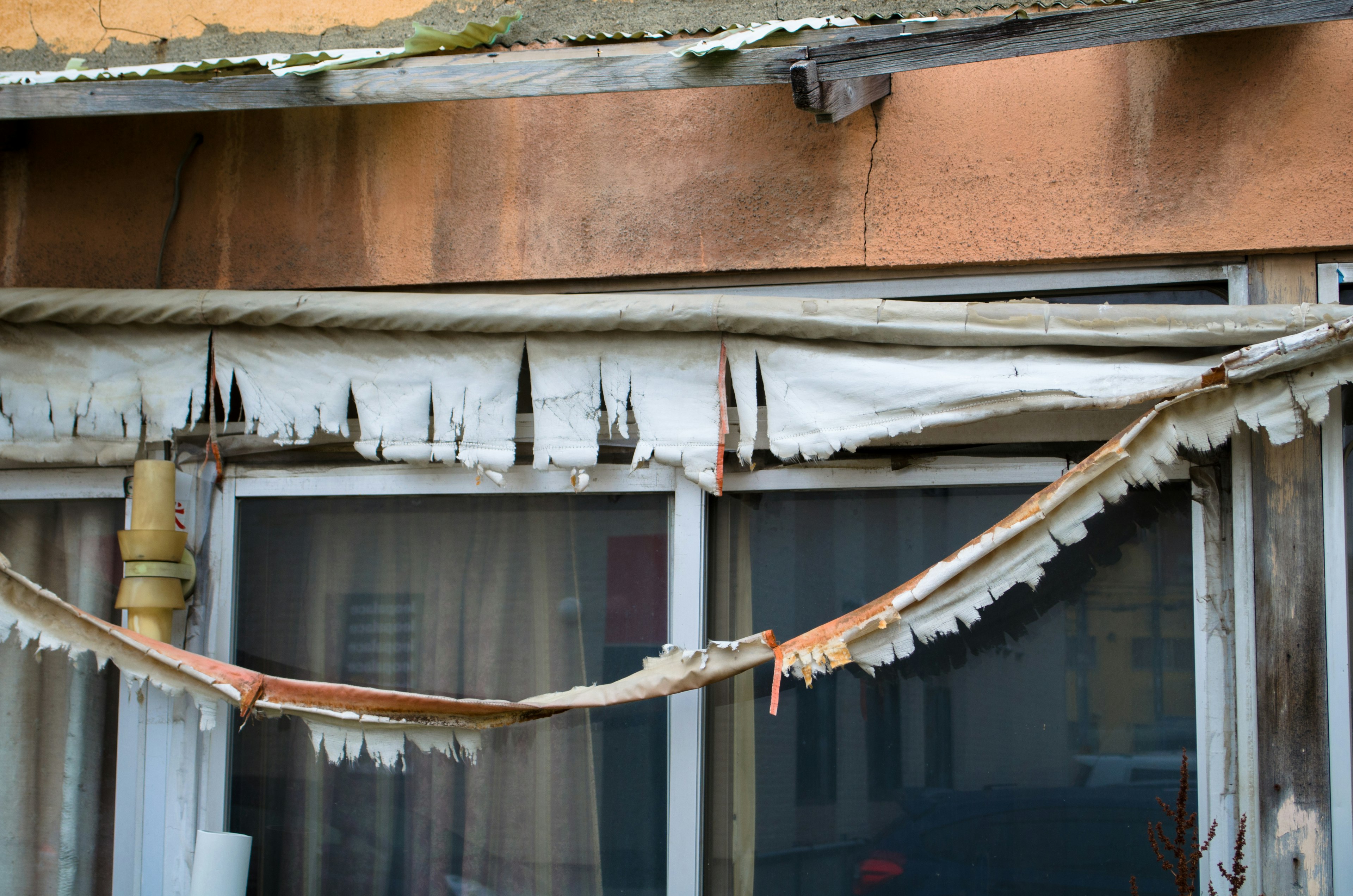 Weathered building exterior showing peeling paint and damaged wood