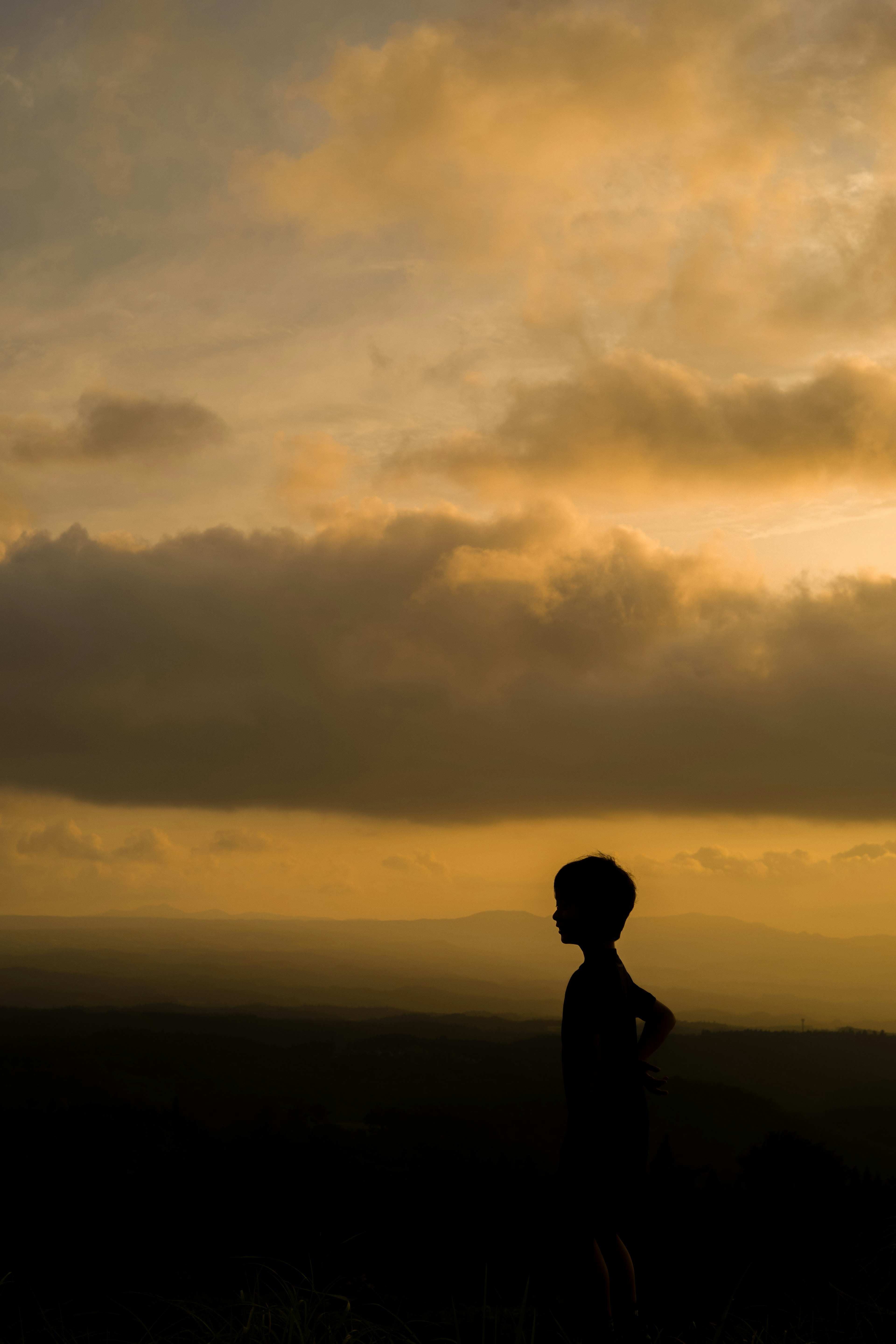 Silhouette di un bambino in piedi contro un cielo al tramonto