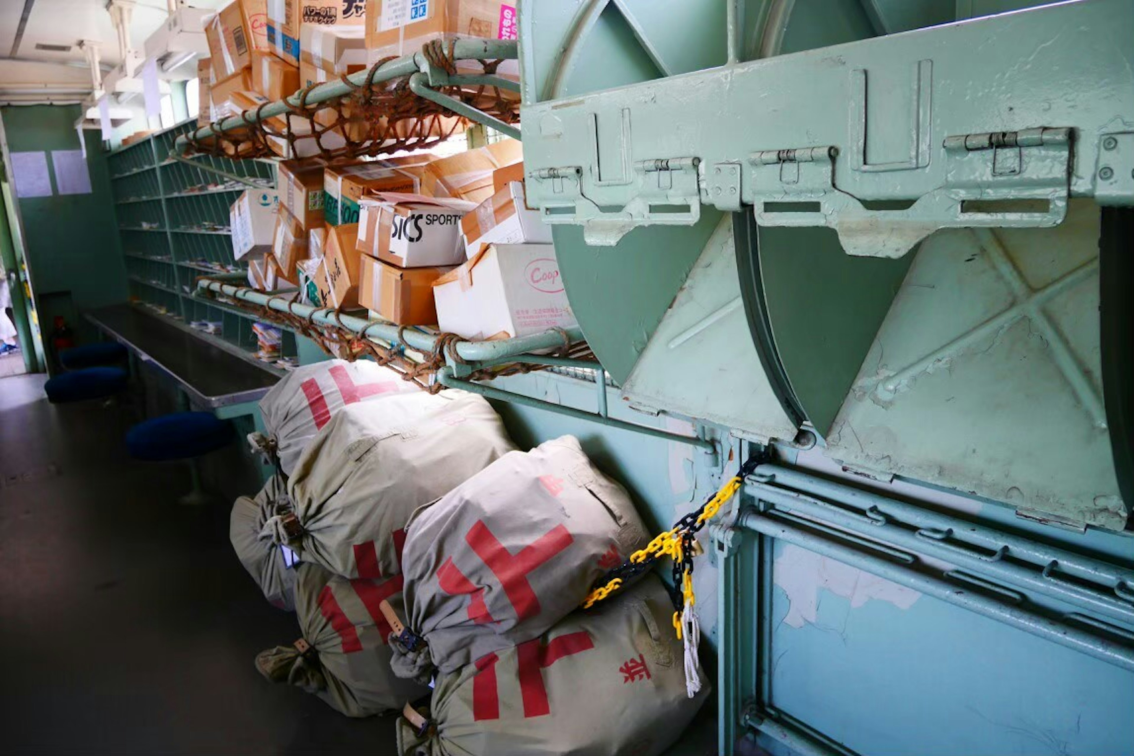 Interior view of a postal room with shelves of packages and large bags