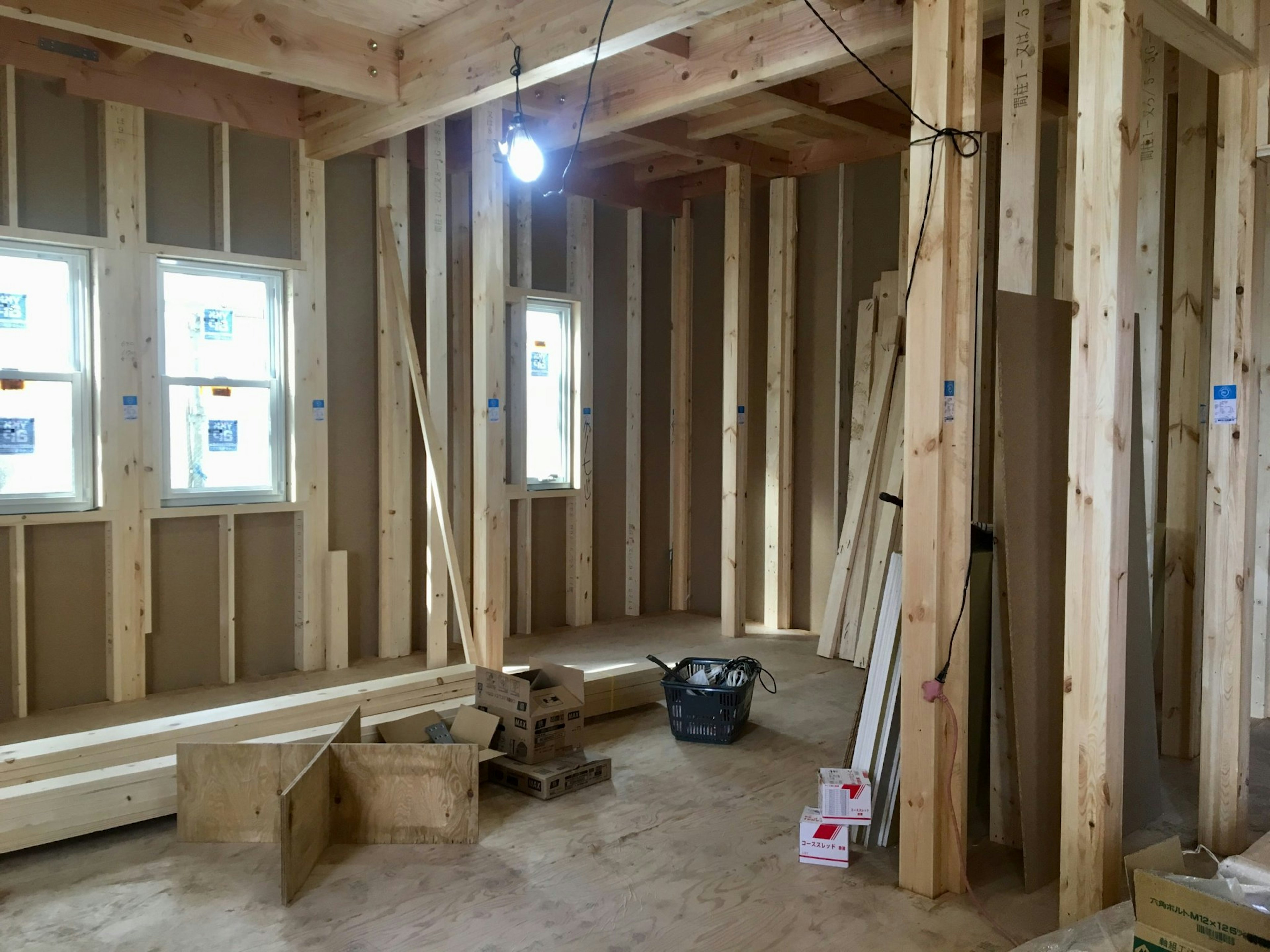 Interior construction of a wooden frame room with bright light fixture hanging from the ceiling