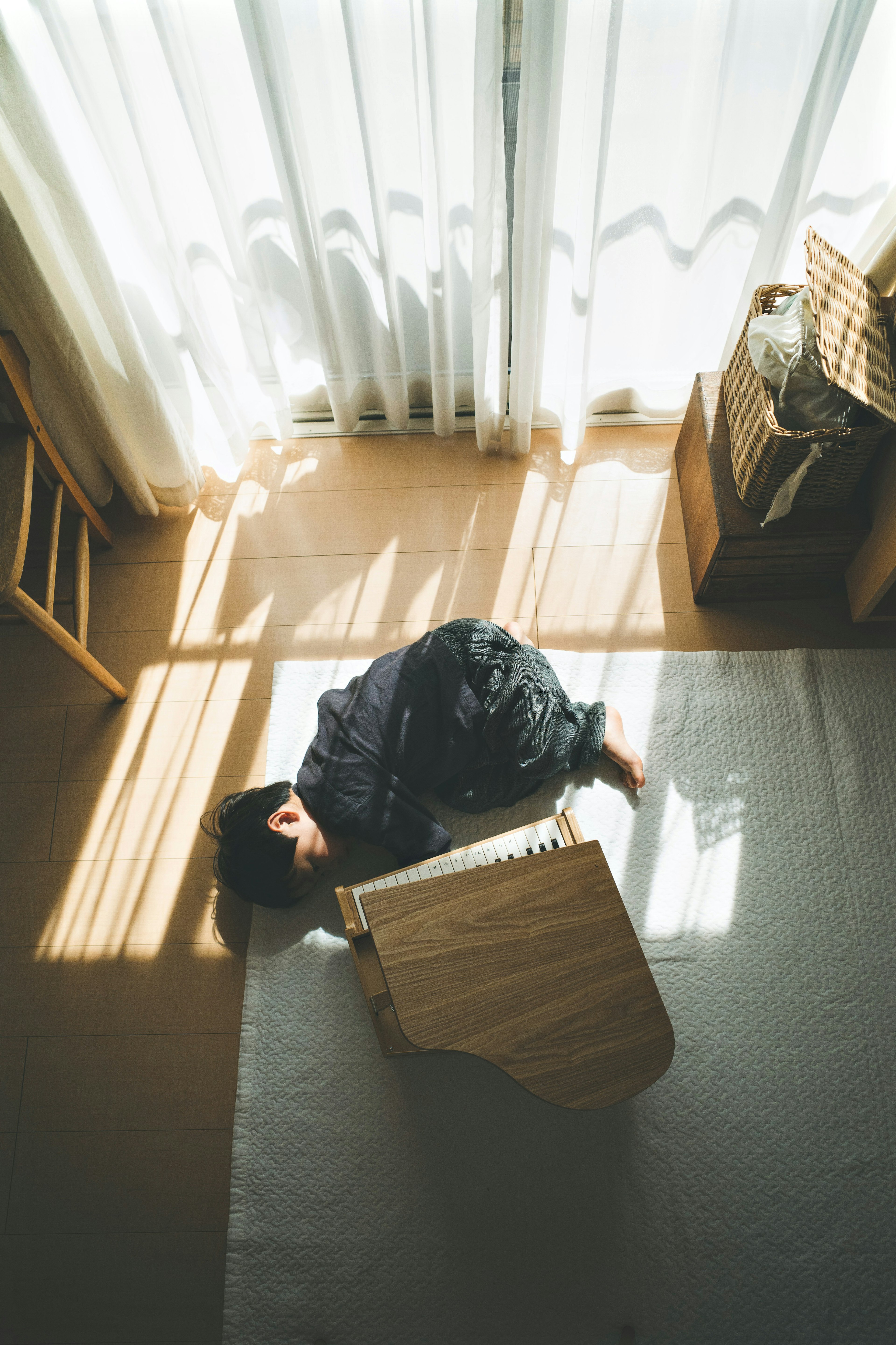 A person curled up sleeping near a bright window with sunlight streaming in