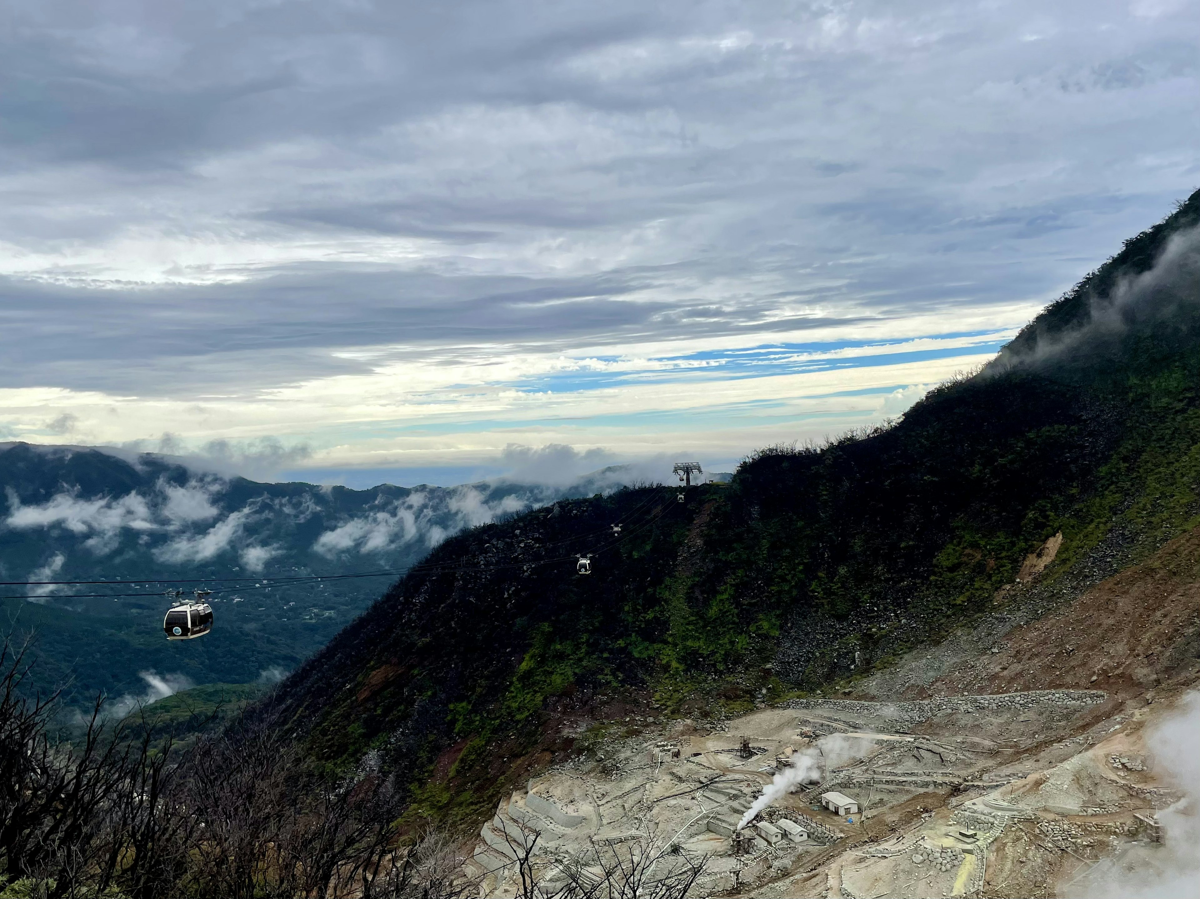 山の斜面にあるロープウェイと雲に覆われた山々の景色