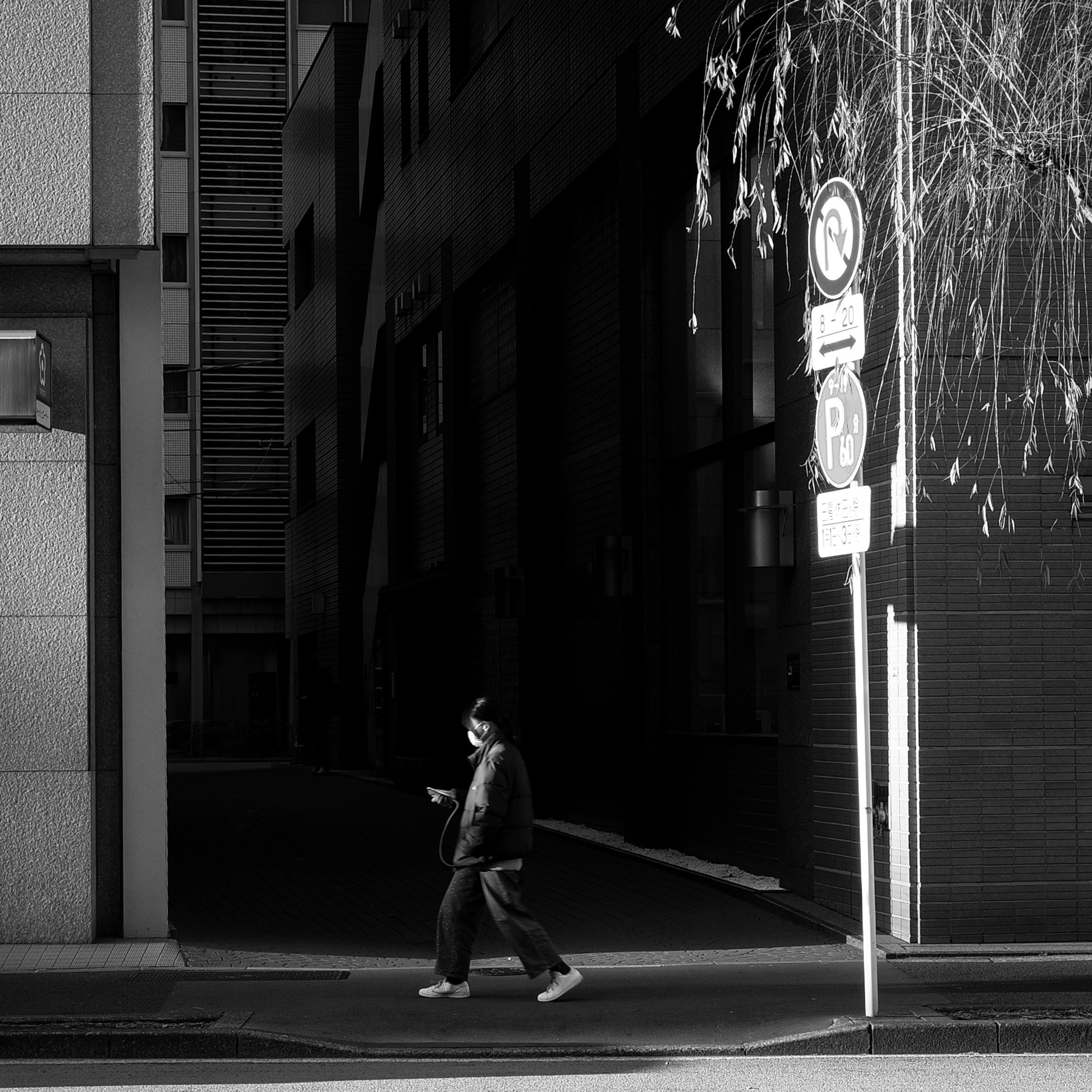 Silhouette of a person walking on a dark street with buildings