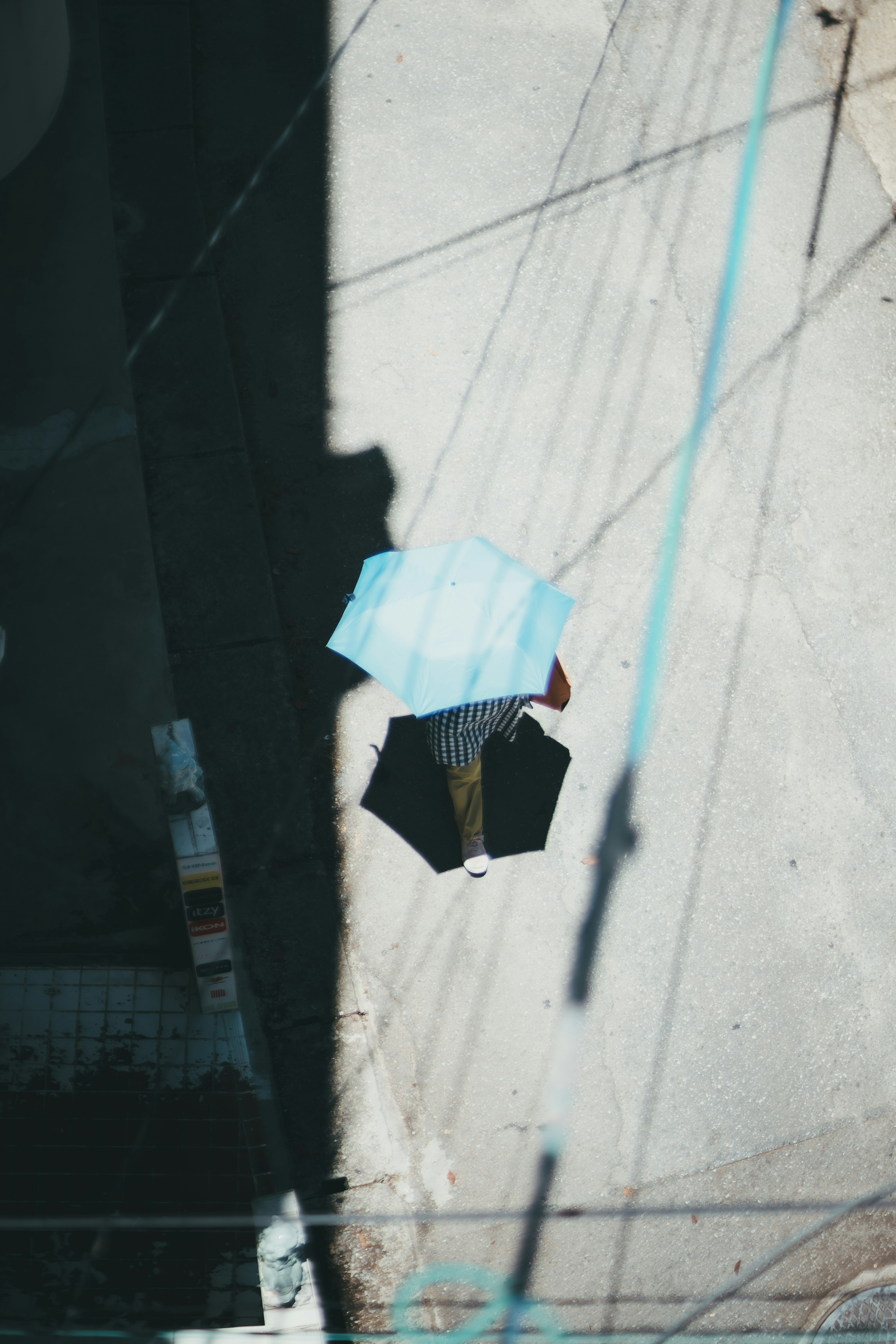 An overhead view of a blue umbrella and a black umbrella on the ground