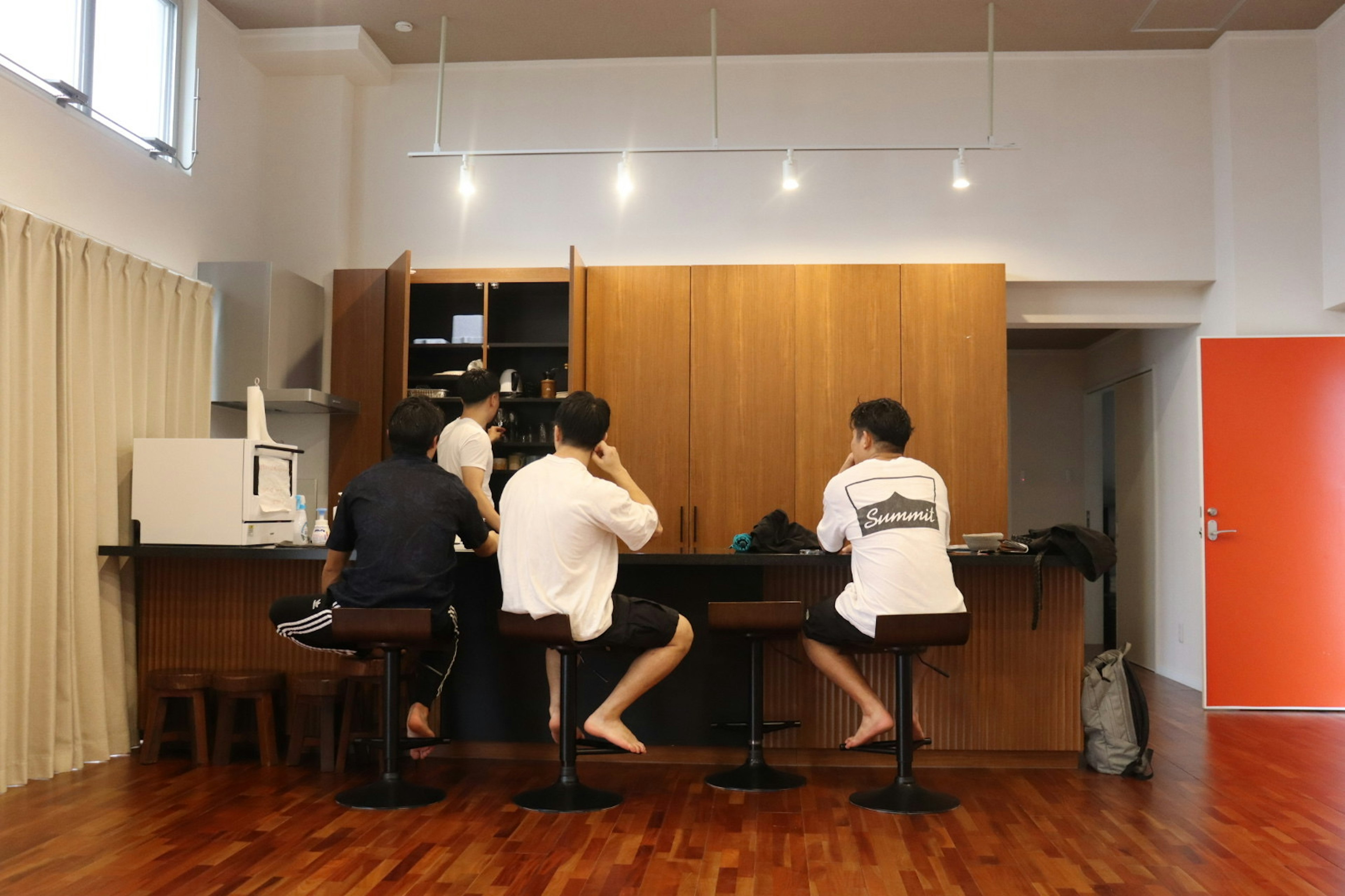 Interior of a room with three men seated at a wooden counter