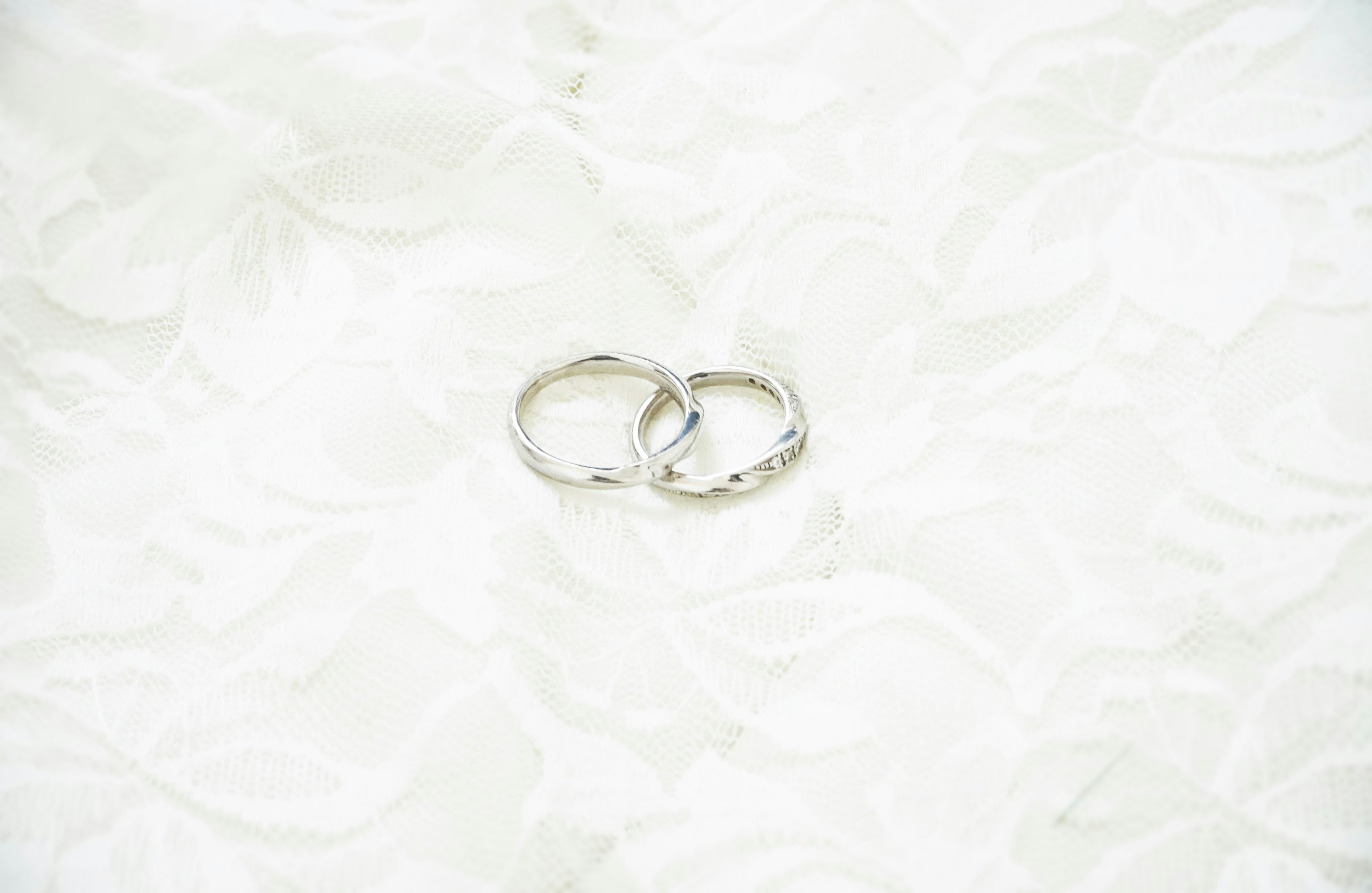 Two silver wedding rings resting on a white fabric surface