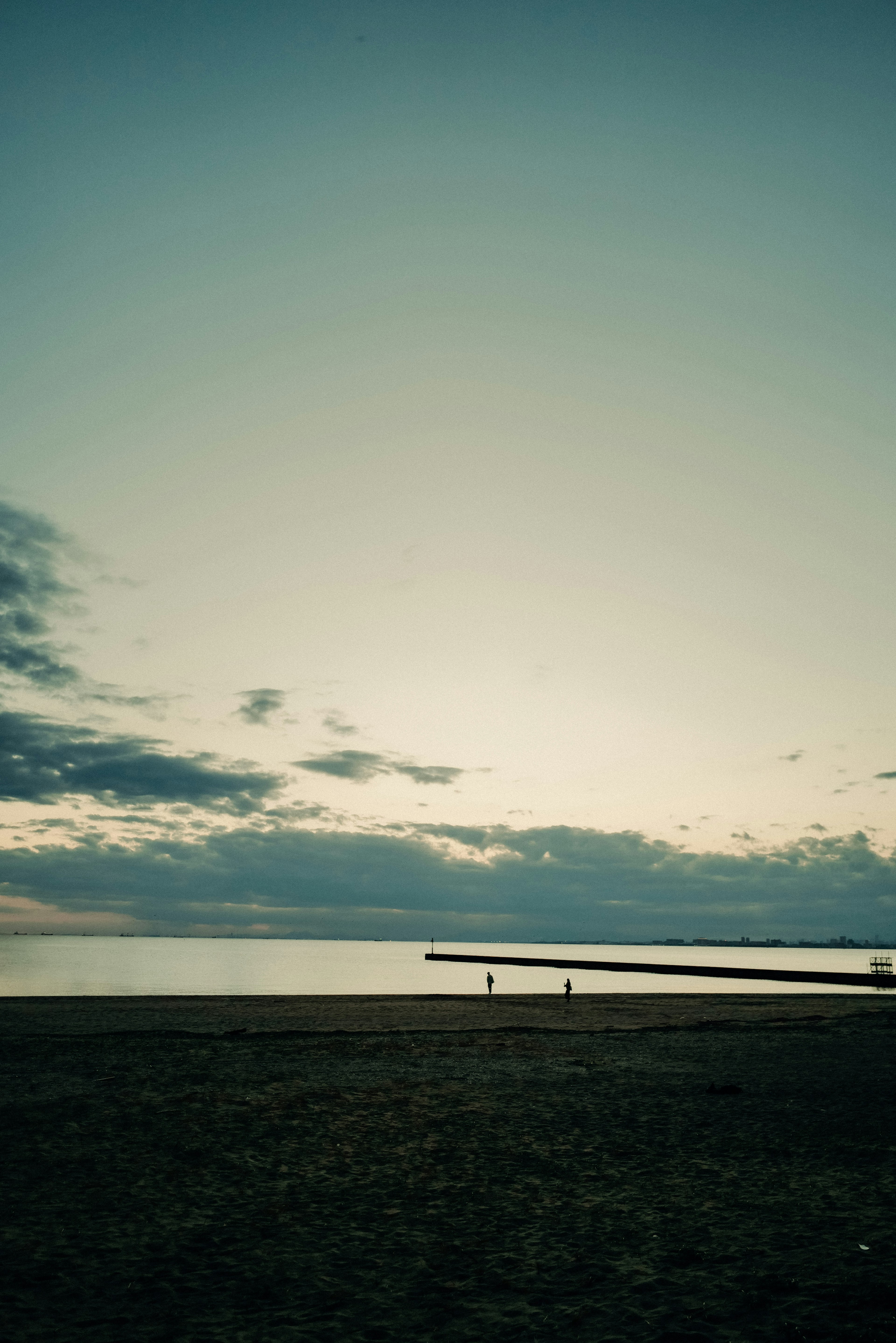 Escena de mar tranquilo y cielo con personas caminando