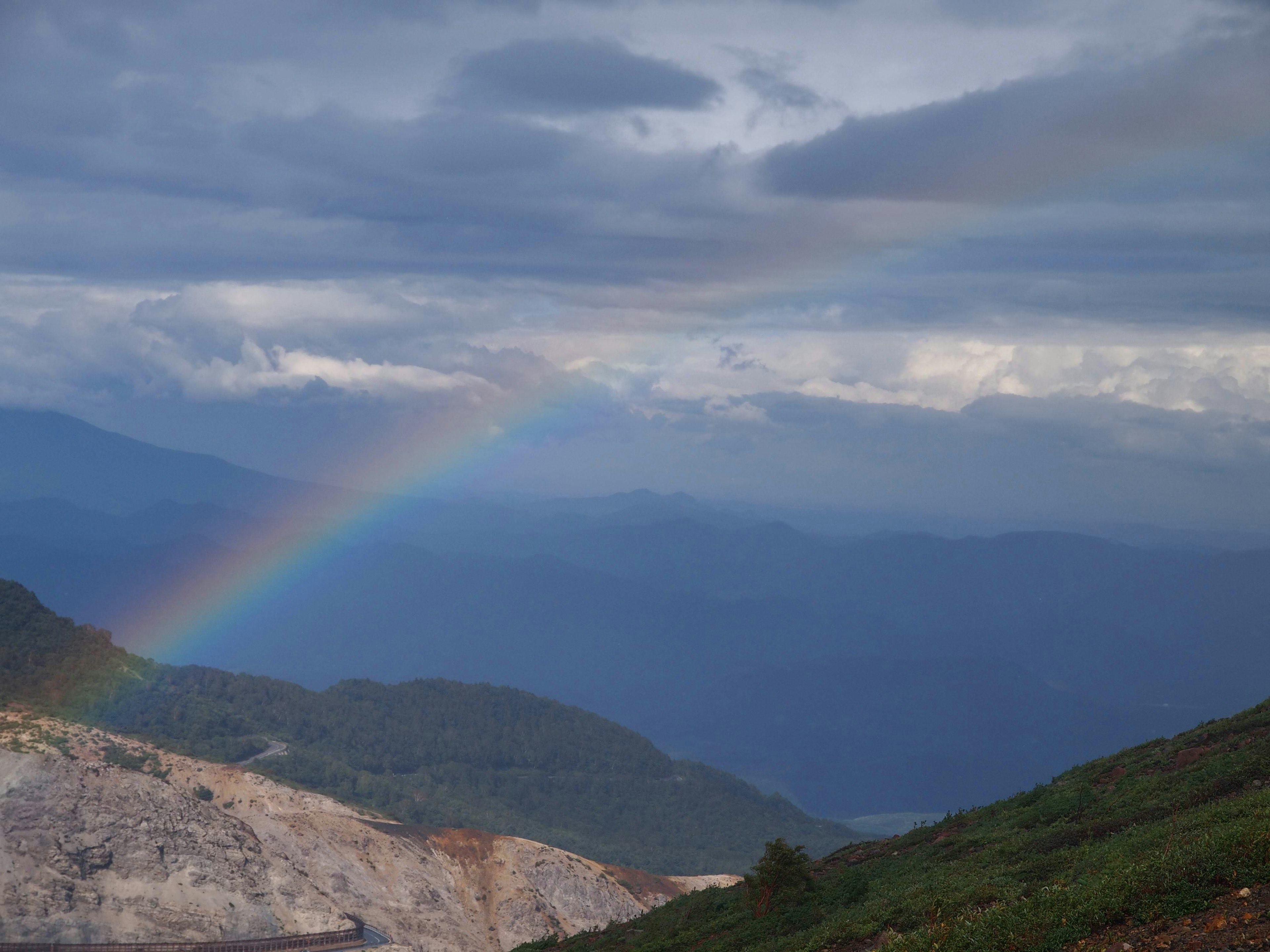 Pelangi di atas pegunungan dengan langit berawan