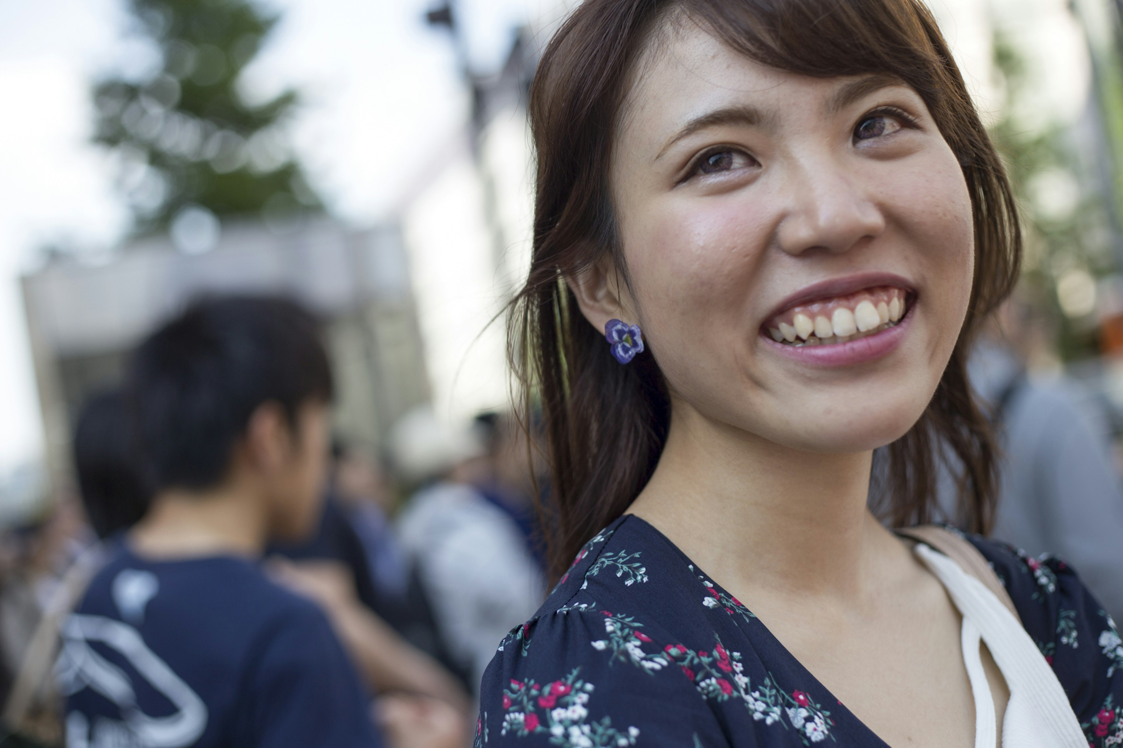 Mujer sonriente con vestido de flores y personas al fondo