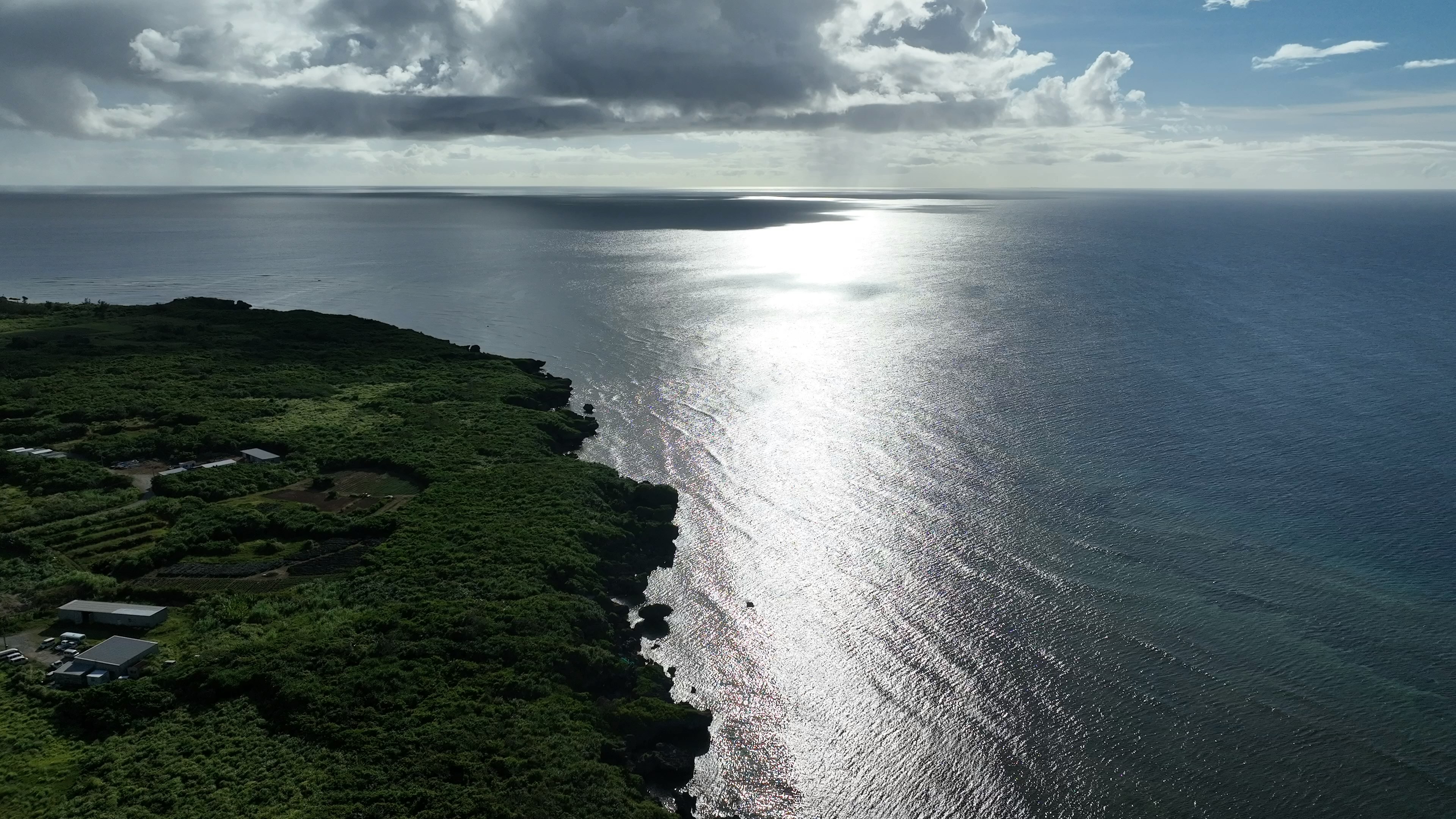 Beautiful landscape of sea and sky with lush green coastline and sun reflection