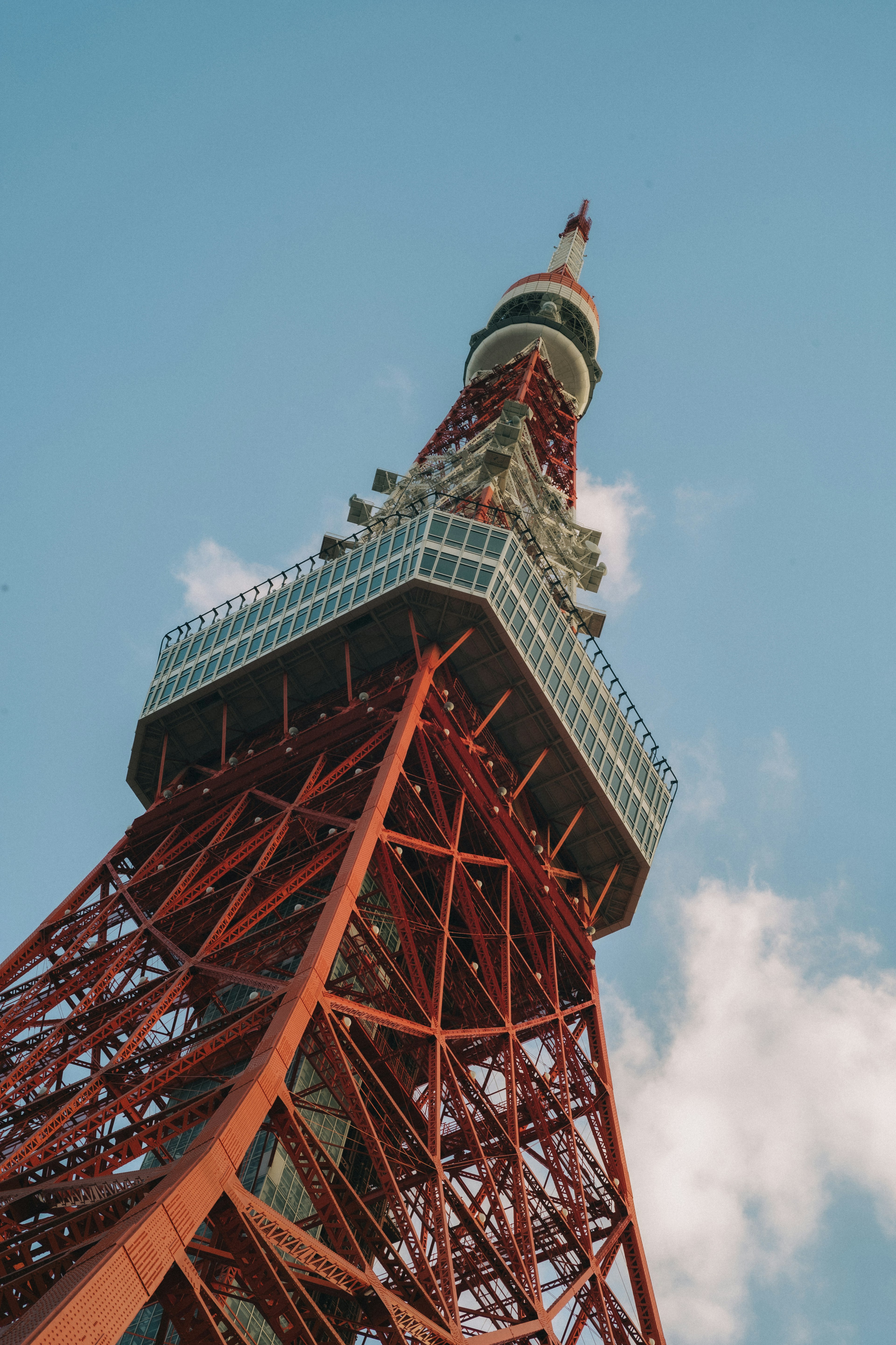 View of Tokyo Tower from below showcasing modern architecture and blue sky