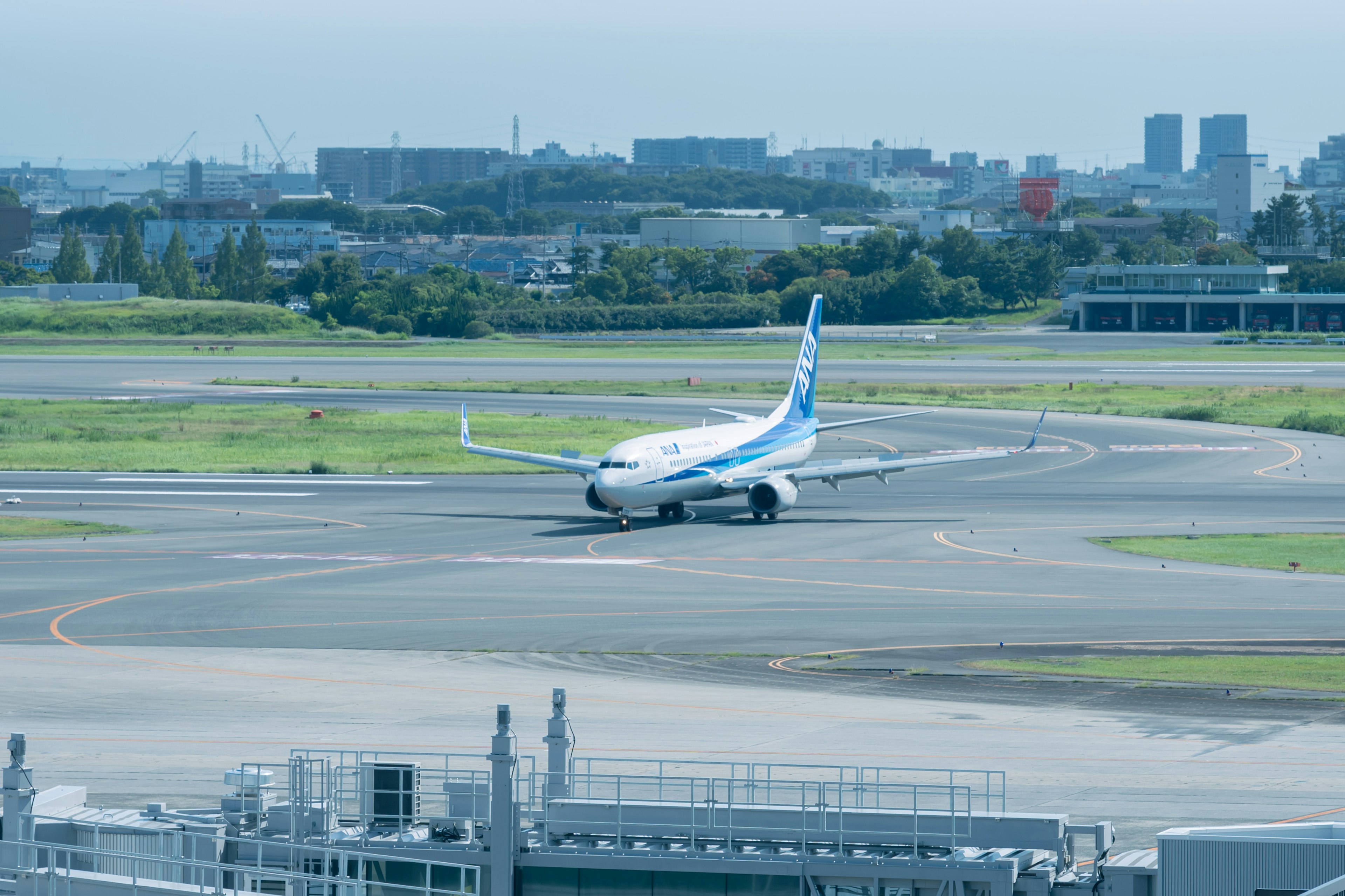 Airplane taxiing on airport runway with city skyline in the background