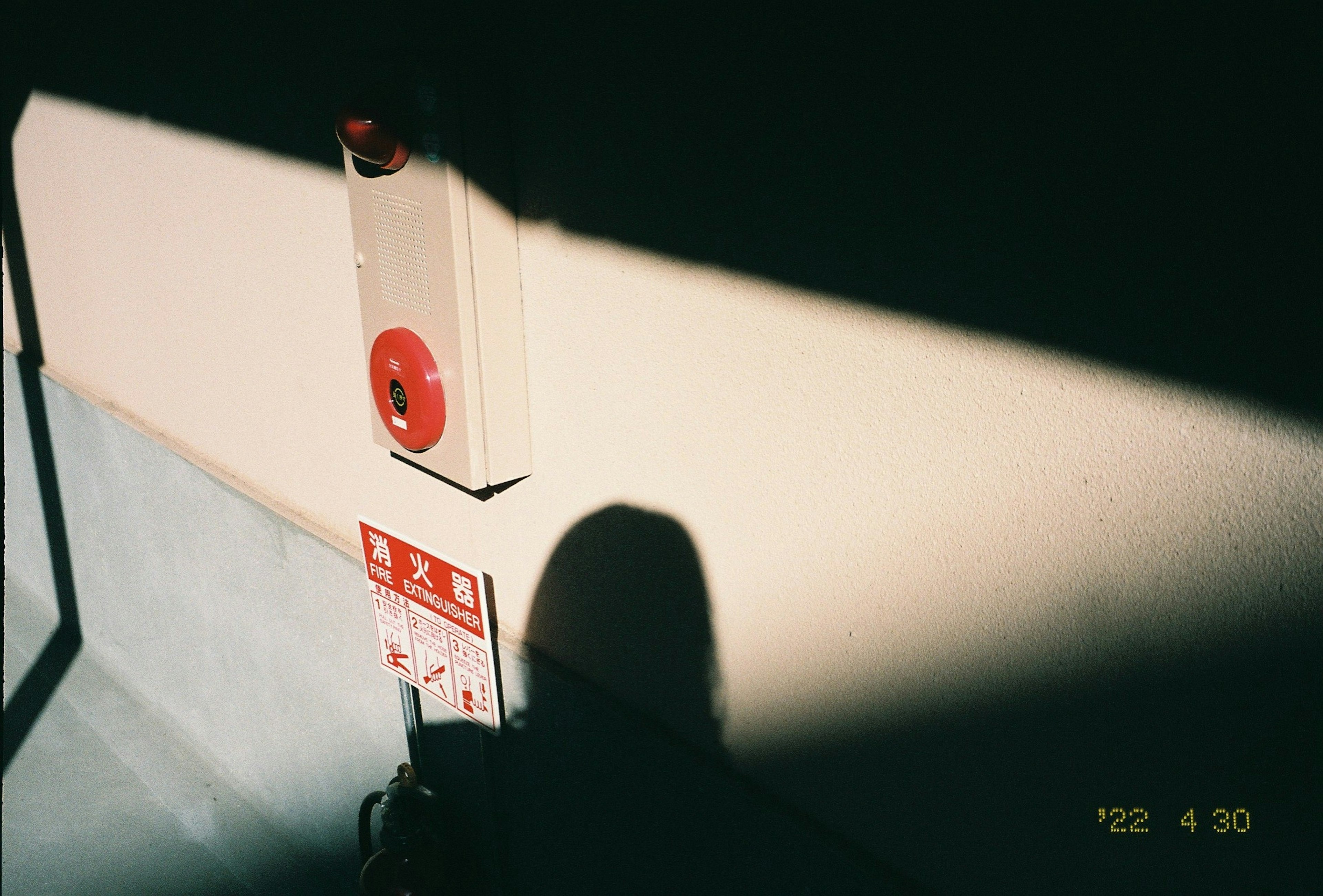 Image showing a red fire alarm button mounted on a wall with shadows