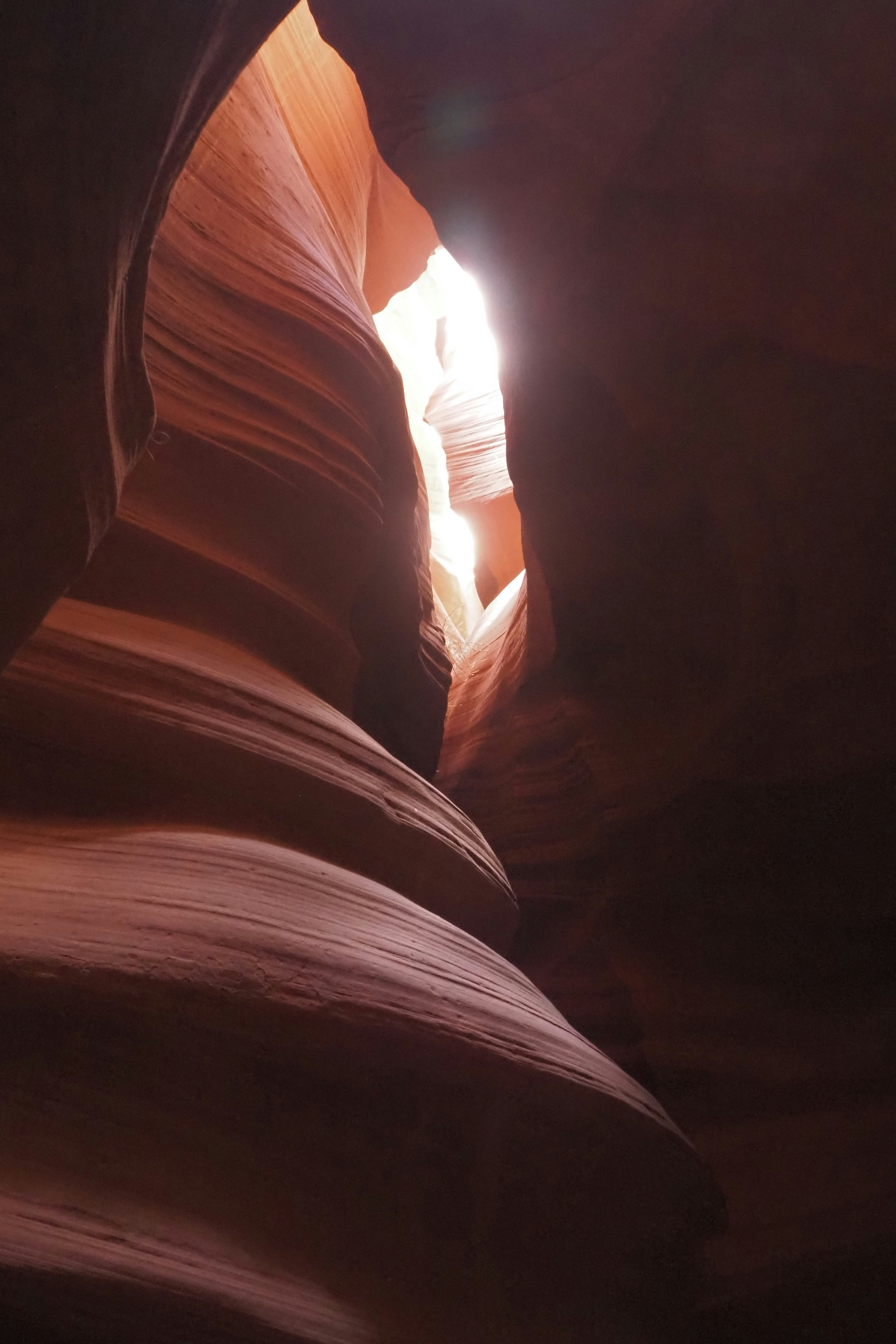 Light streaming through a narrow opening in Antelope Canyon showcasing red rock layers