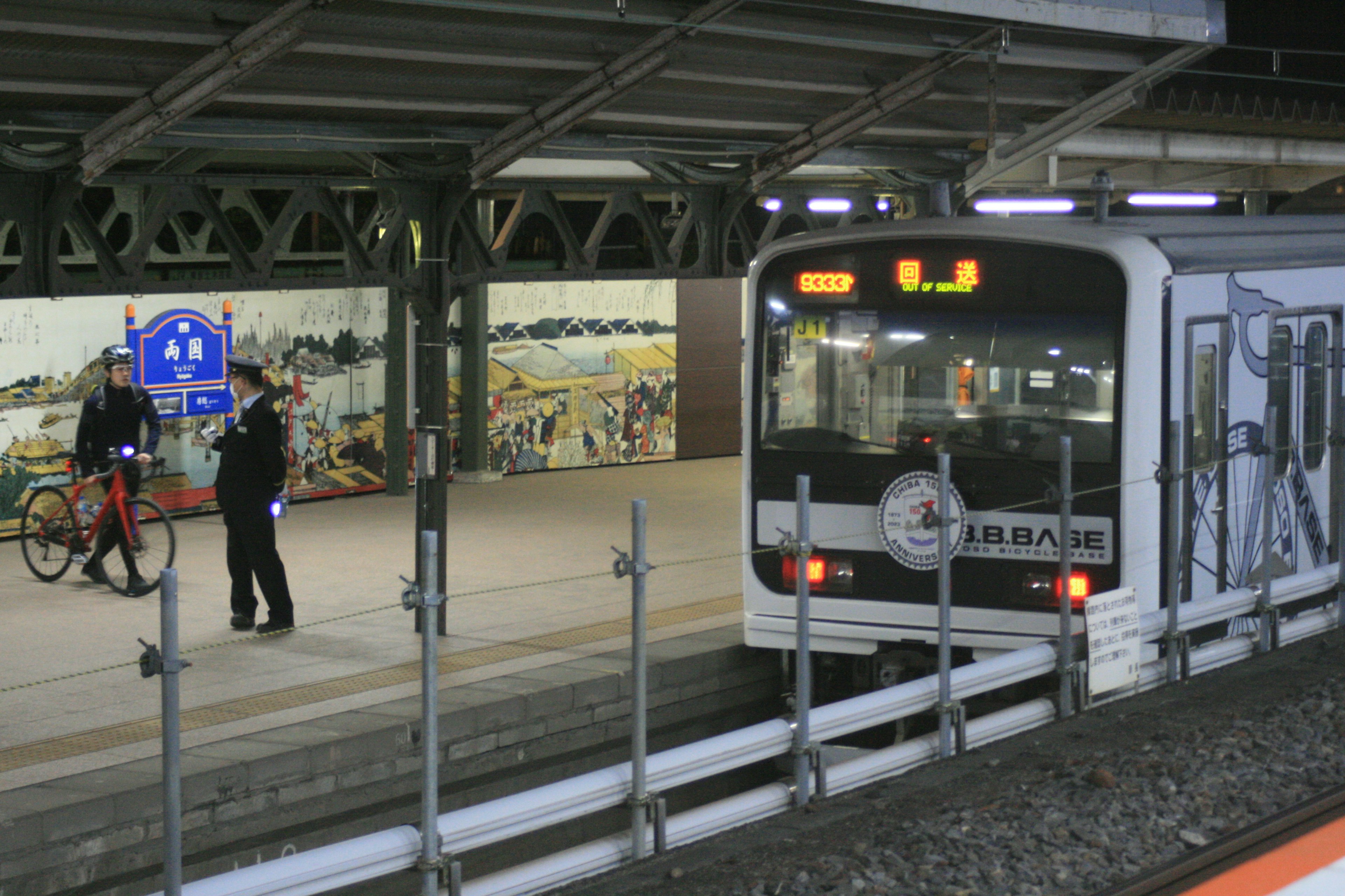 Train stopped at a station platform with a man on a bicycle