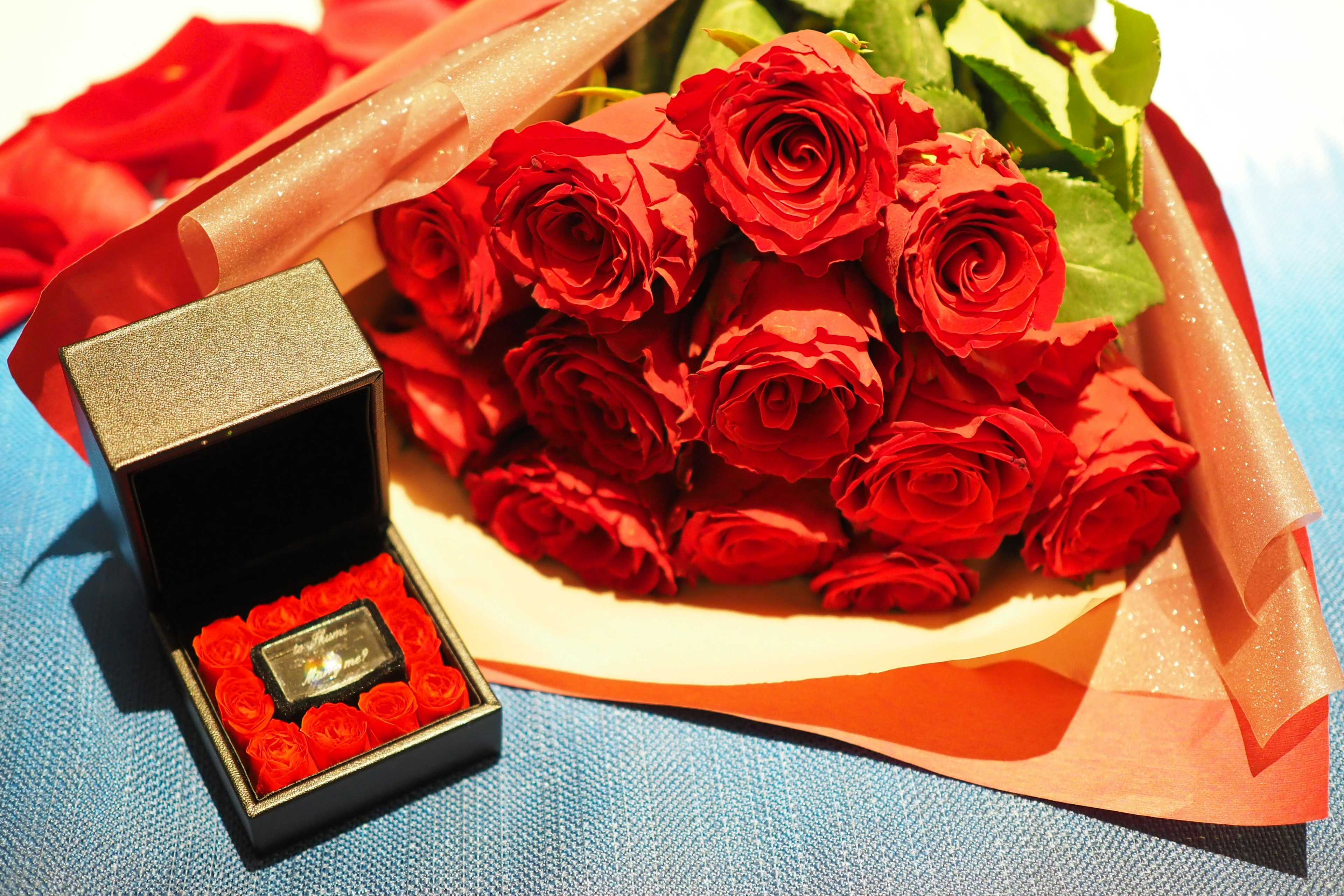 A beautiful scene featuring a bouquet of red roses and a ring box