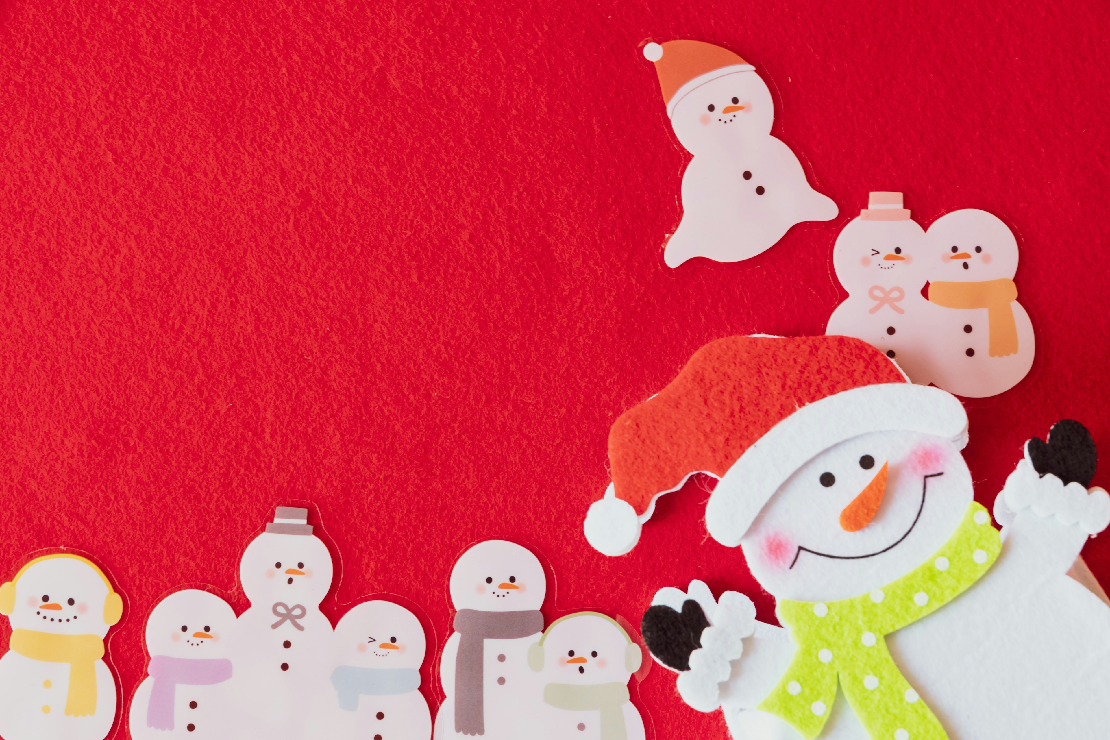 Colorful snowmen with a Santa hat on a red background