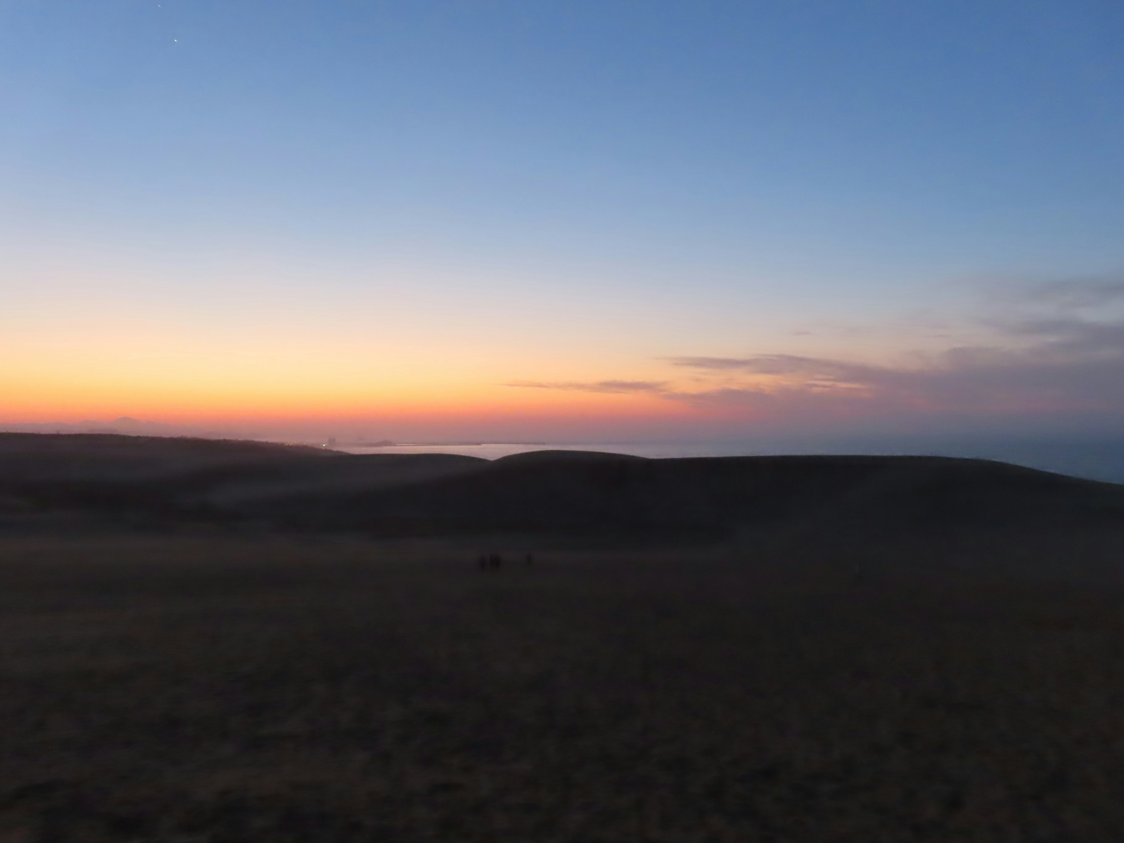 Silhouette di colline contro un cielo colorato al tramonto