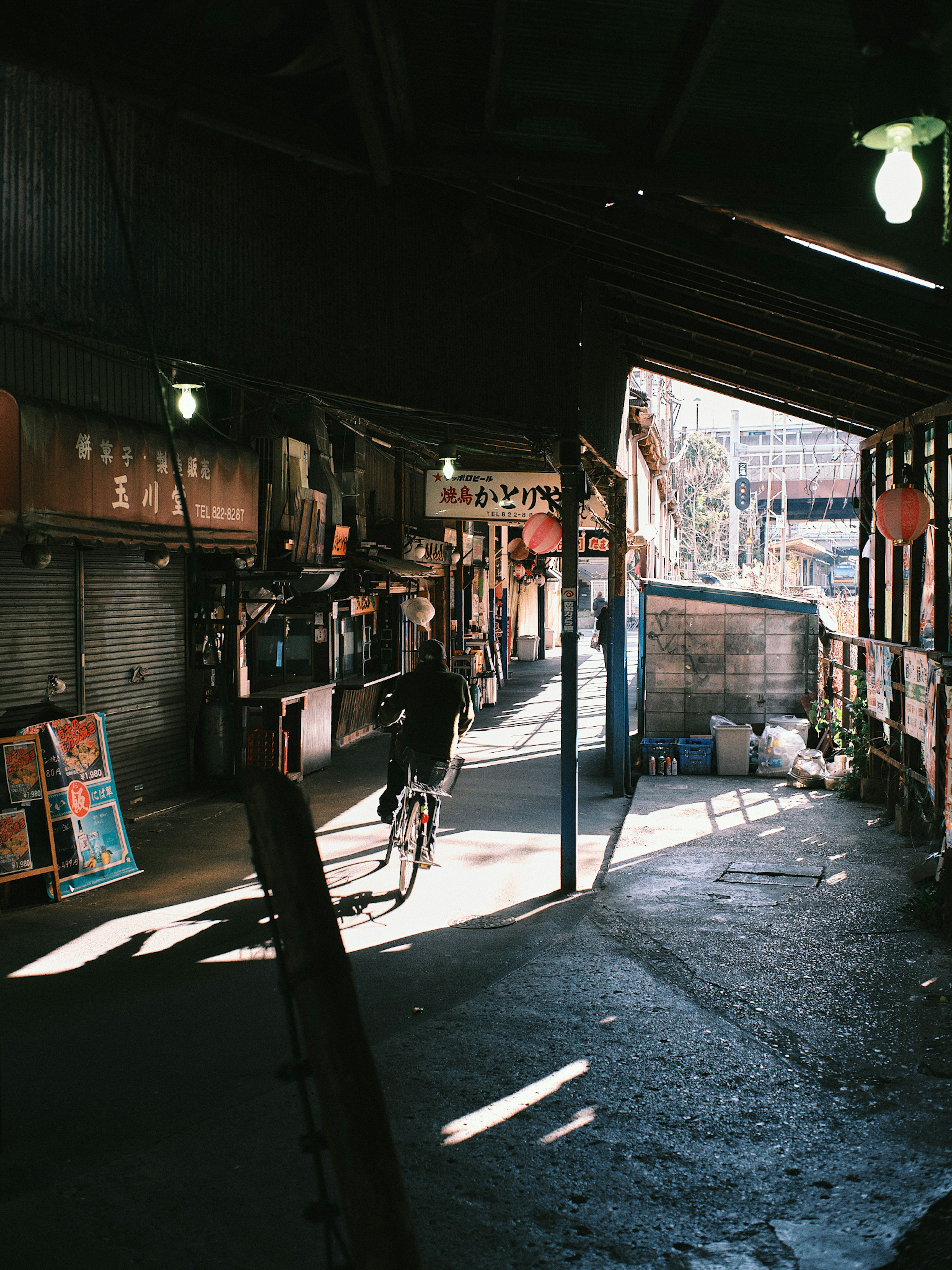 Narrow passage with a person pushing a bicycle and light streaming in