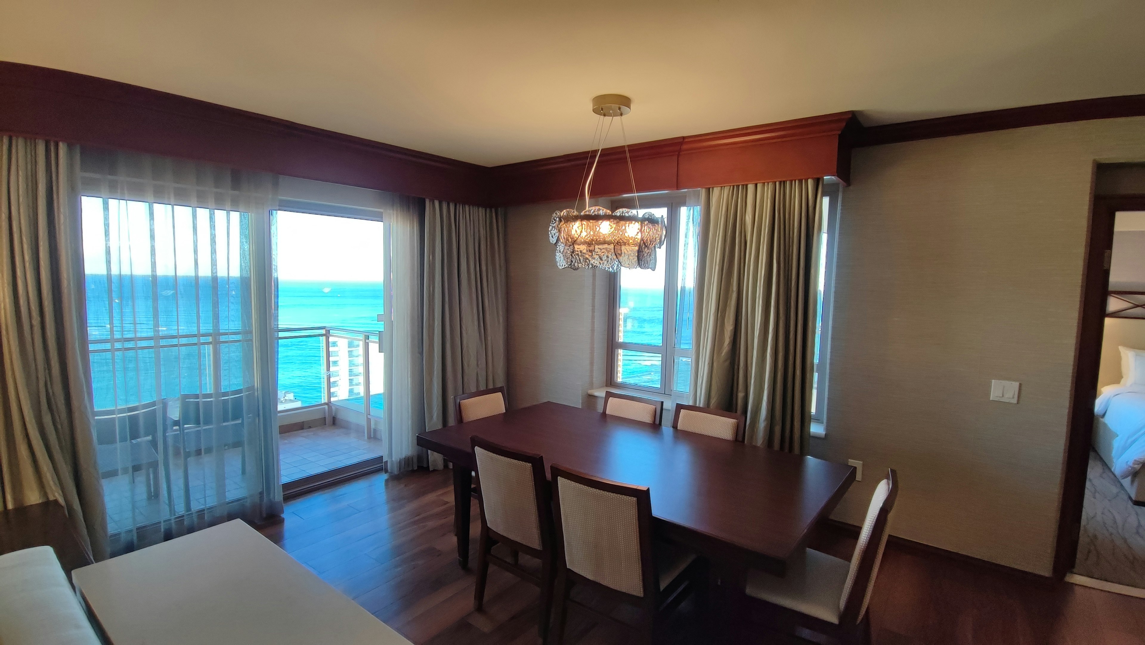 Foto interior de un comedor con vista al océano con grandes ventanas y muebles simples