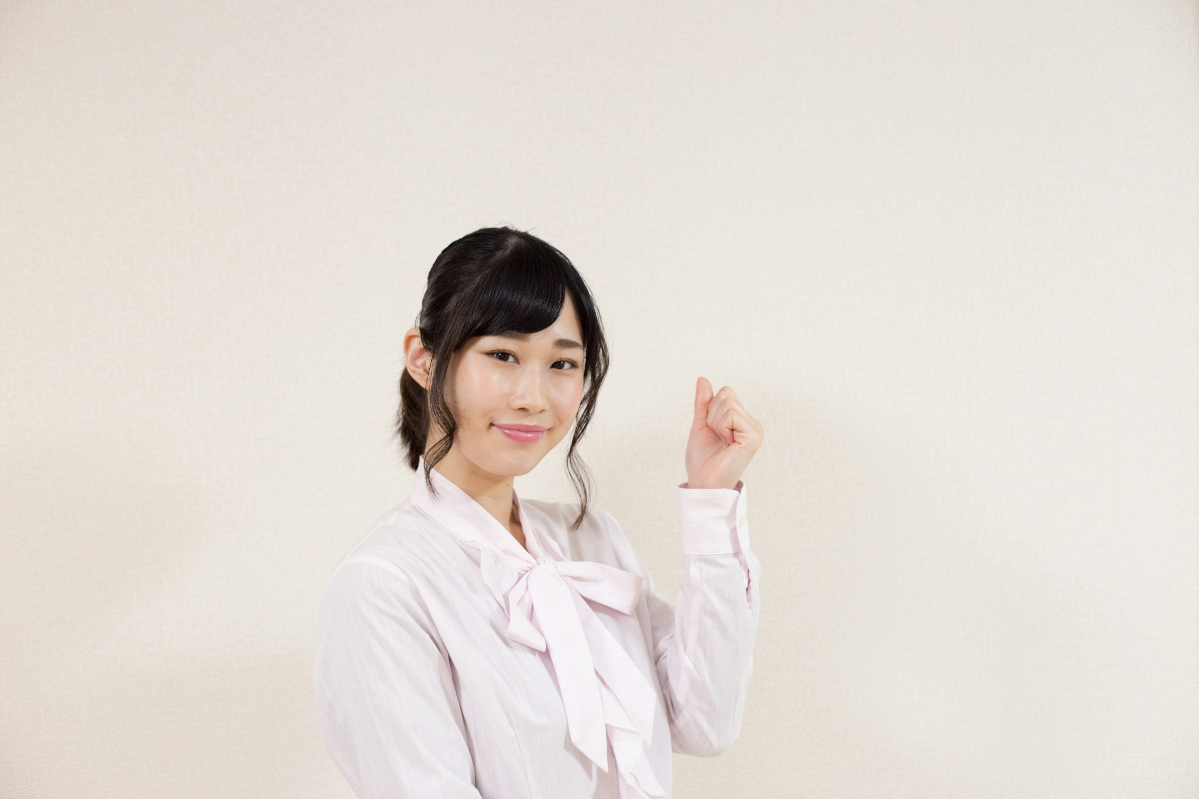 A smiling woman holding up her finger in front of a white background