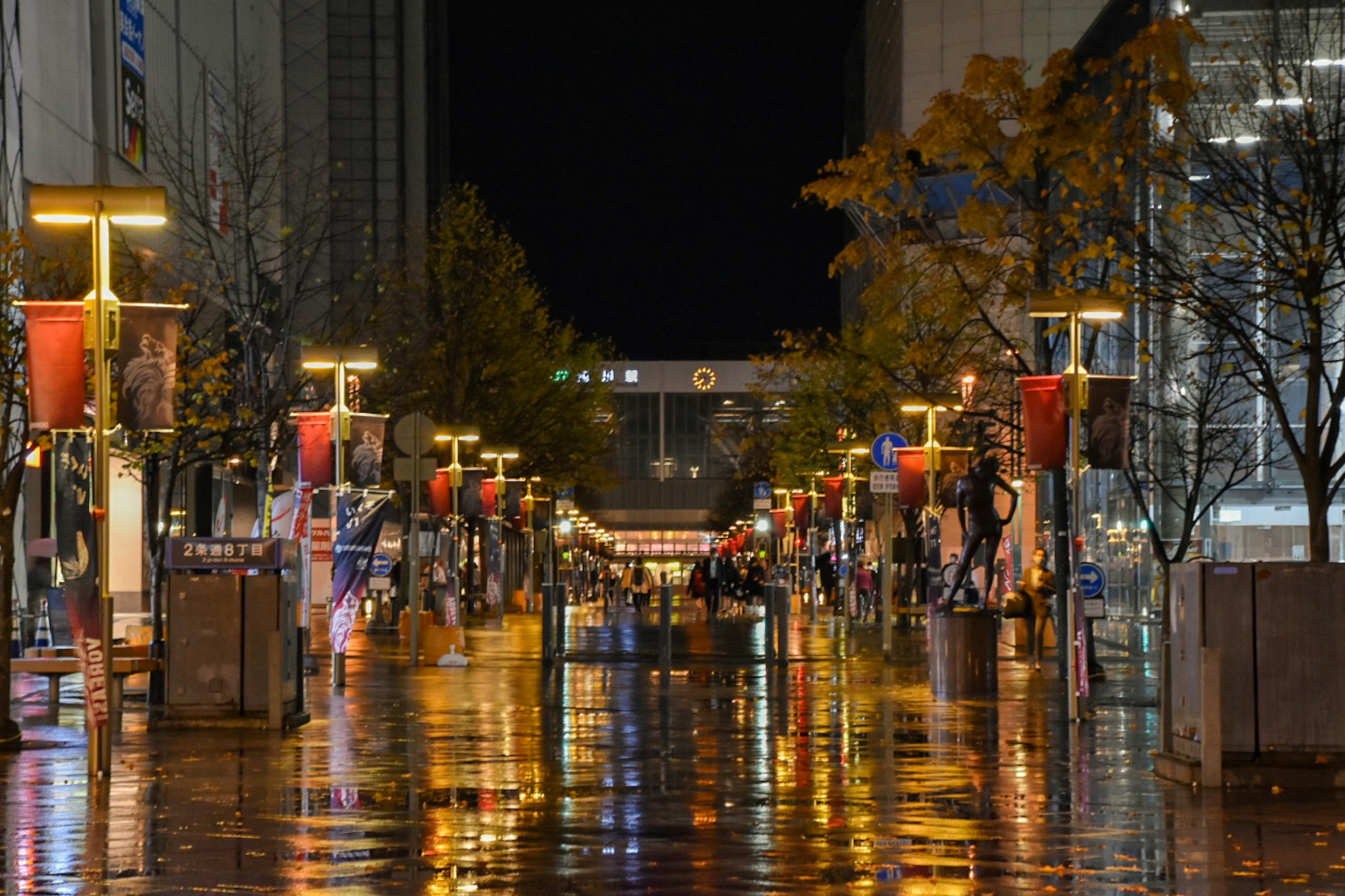 Nachtszene einer Stadtstraße mit nassem Pflaster und Reflexionen von Straßenlaternen