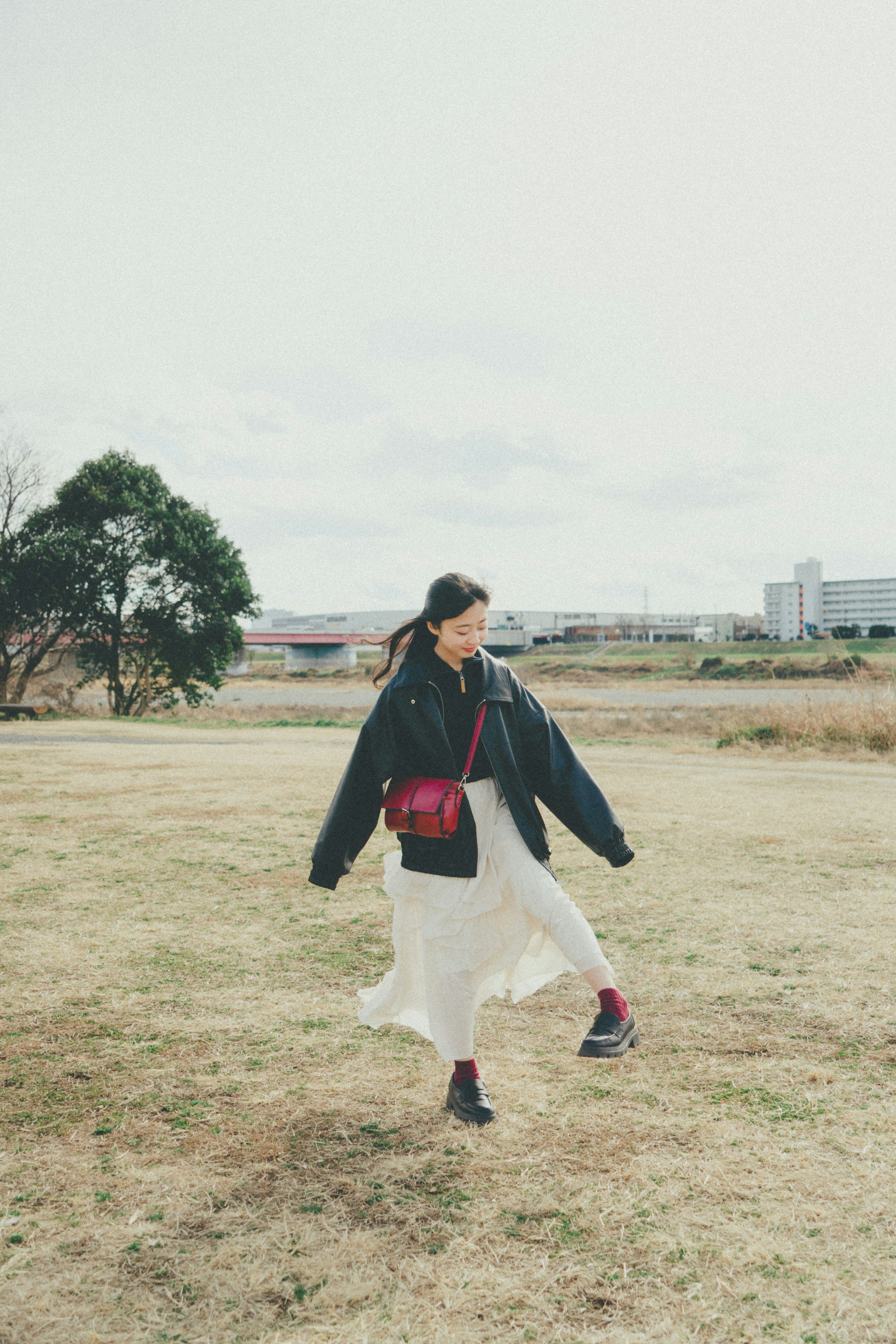 A woman wearing a flowing white skirt walking in a field