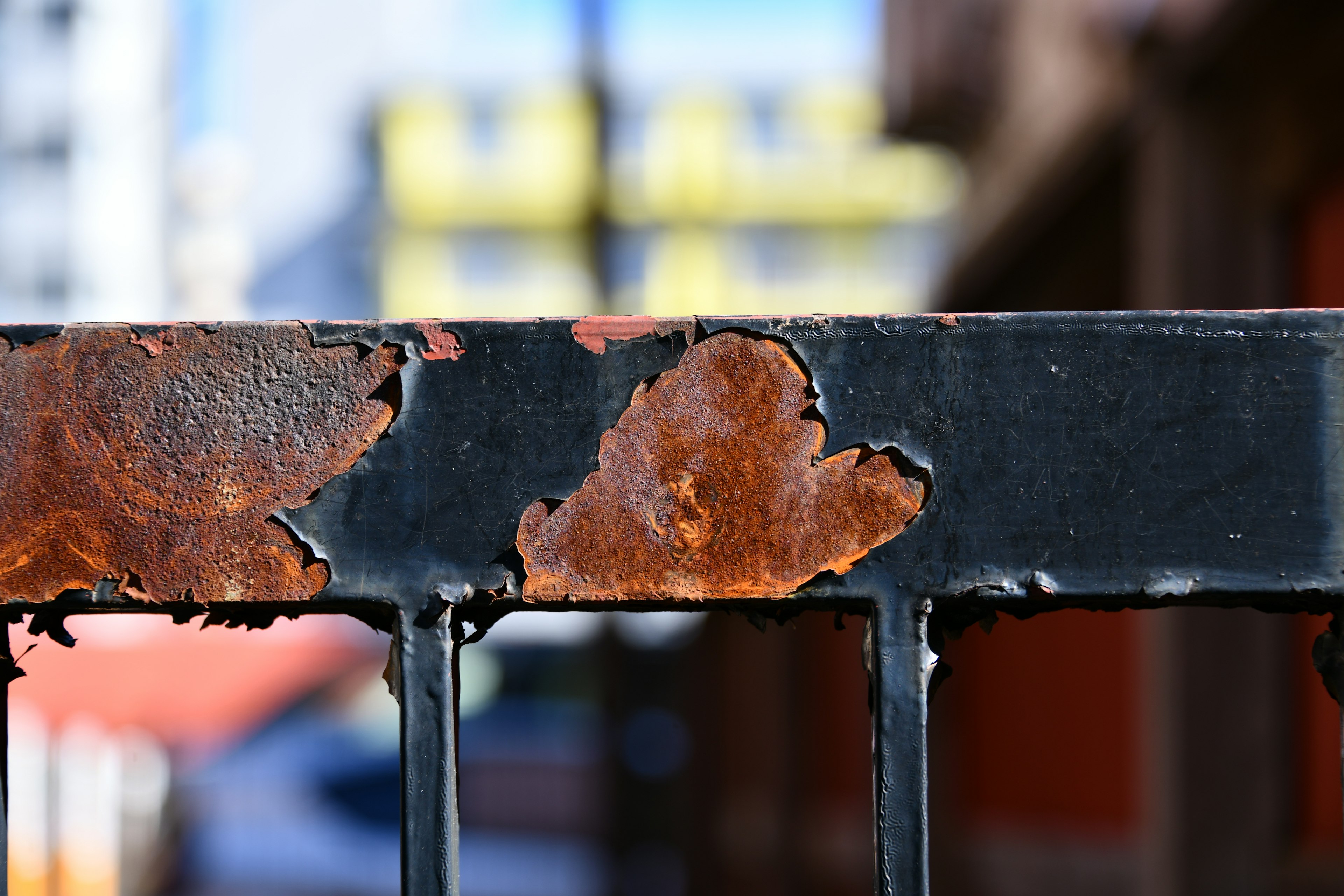 Close-up of a rusty metal fence with notable peeling areas