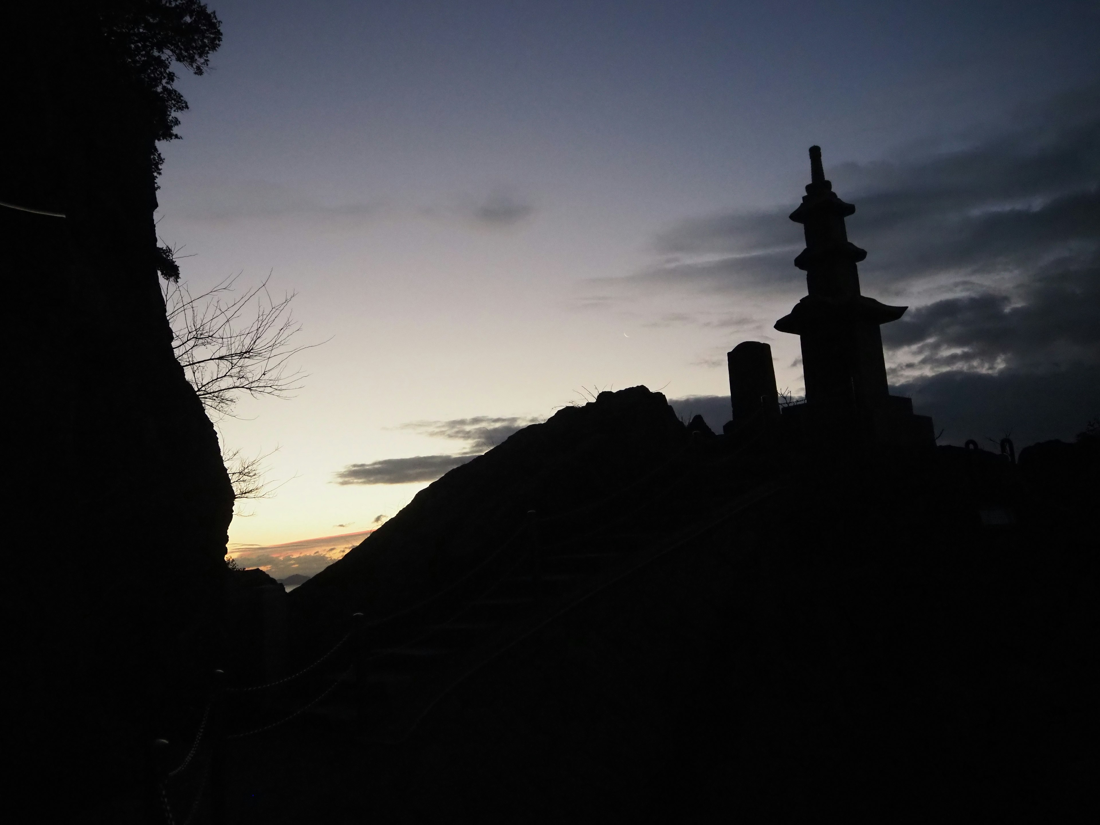 夕暮れ時の山のシルエットに浮かぶ塔と雲