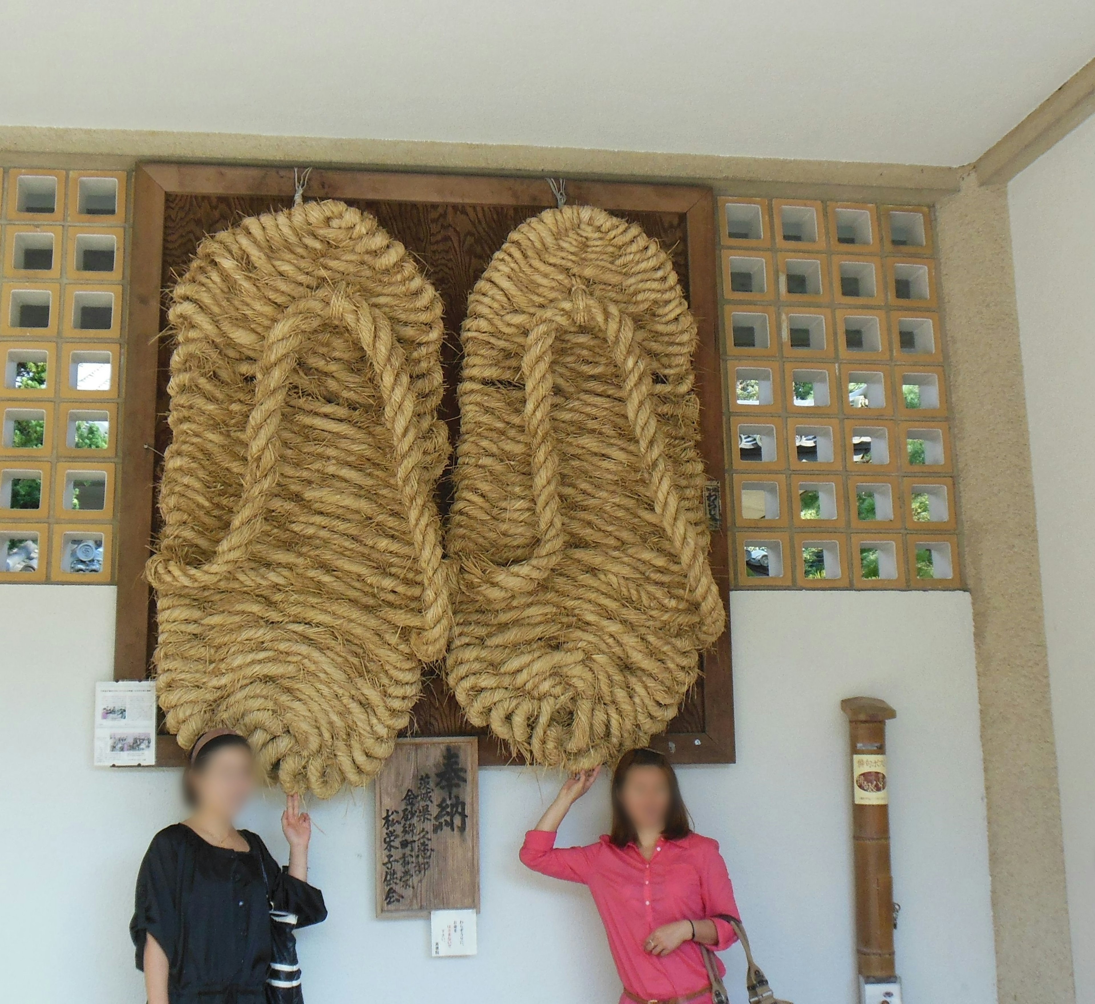 Two women interacting with a large rope sandal art installation