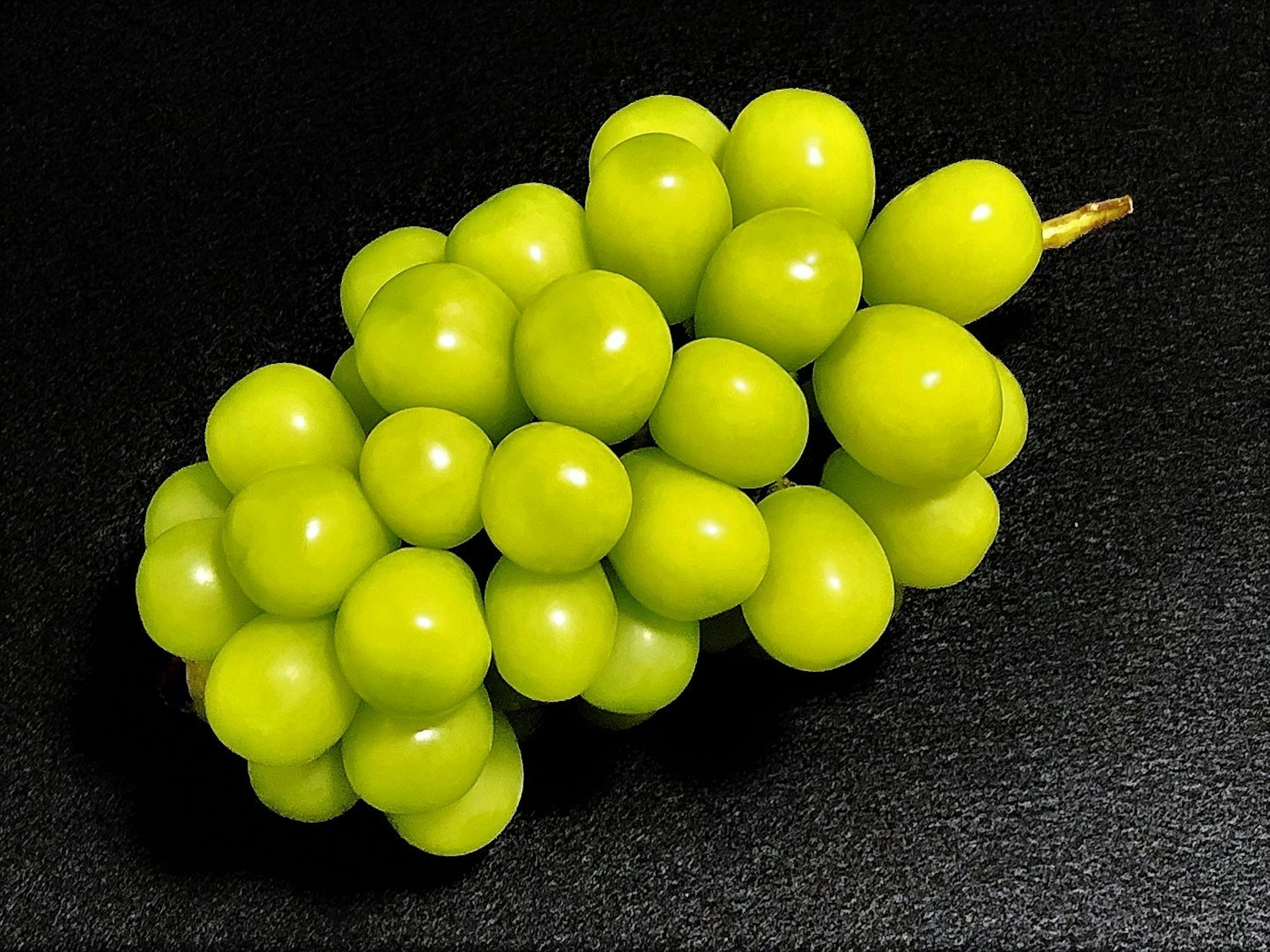 Un racimo de uvas verdes sobre un fondo negro