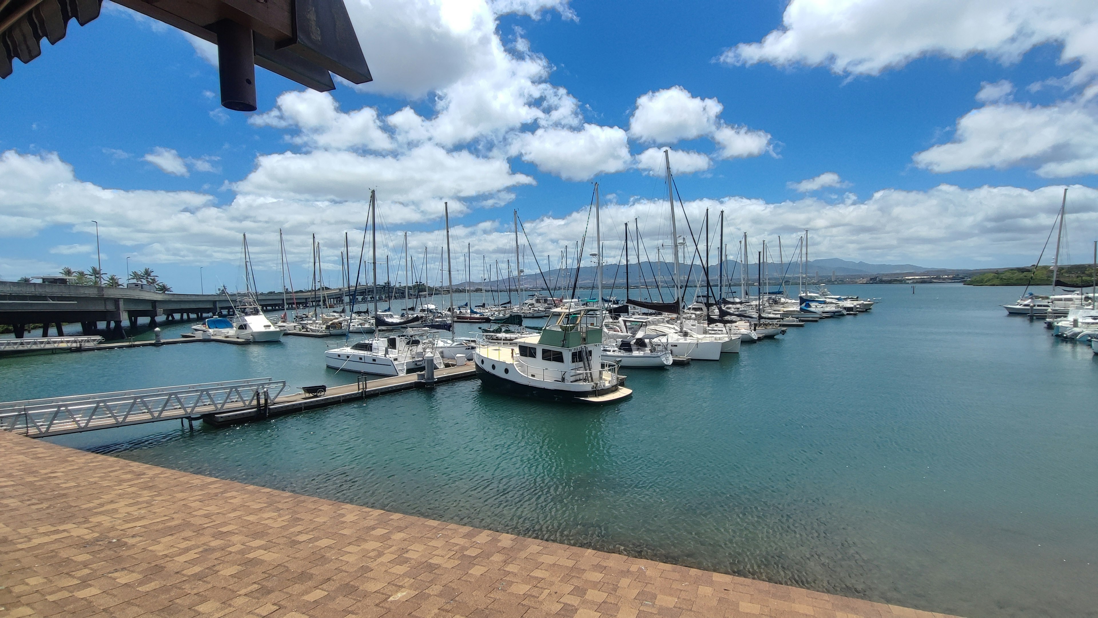 Vista escénica del puerto deportivo con barcos y yates amarrados bajo un cielo azul y nubes blancas