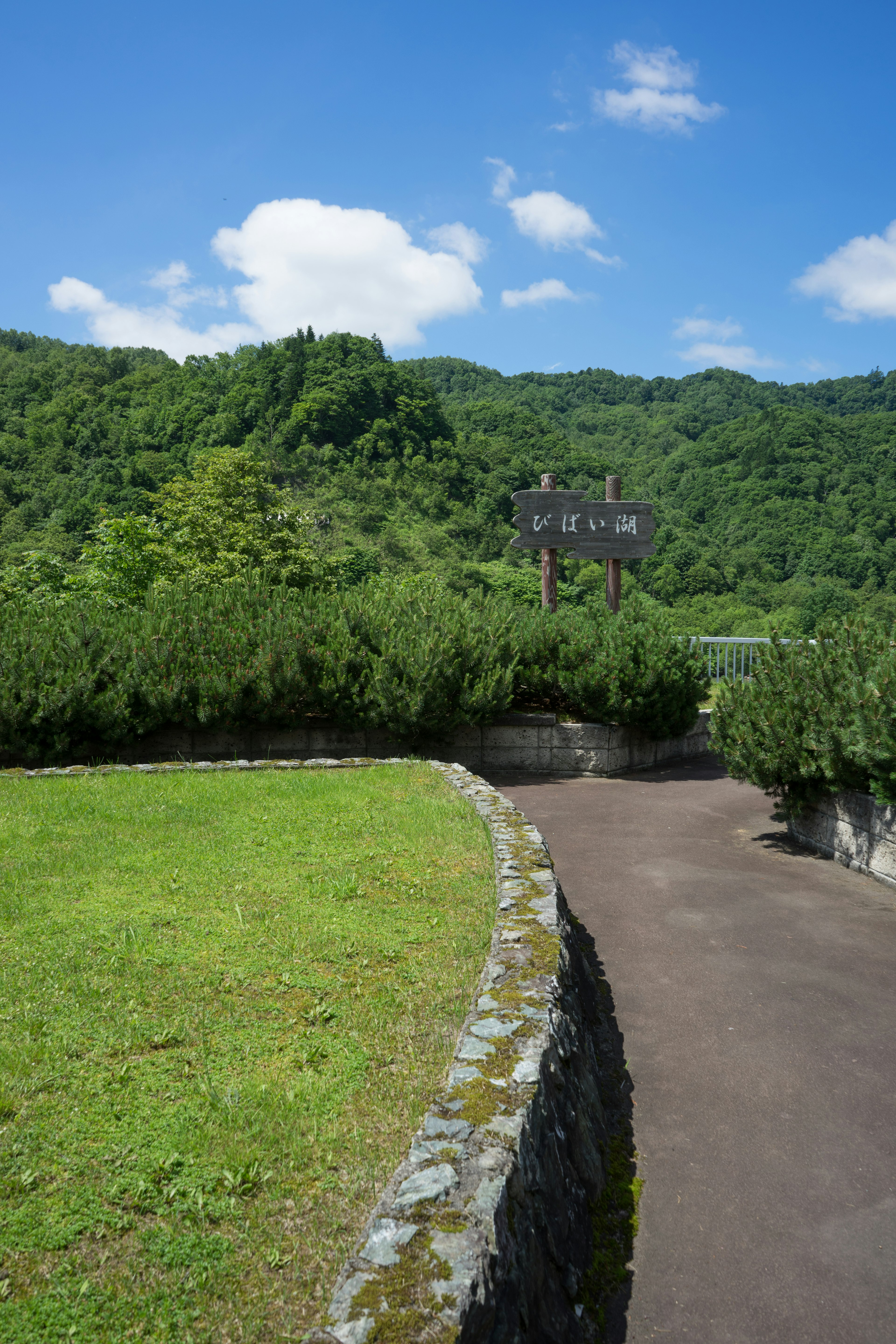 Winding path under a blue sky with lush green hills