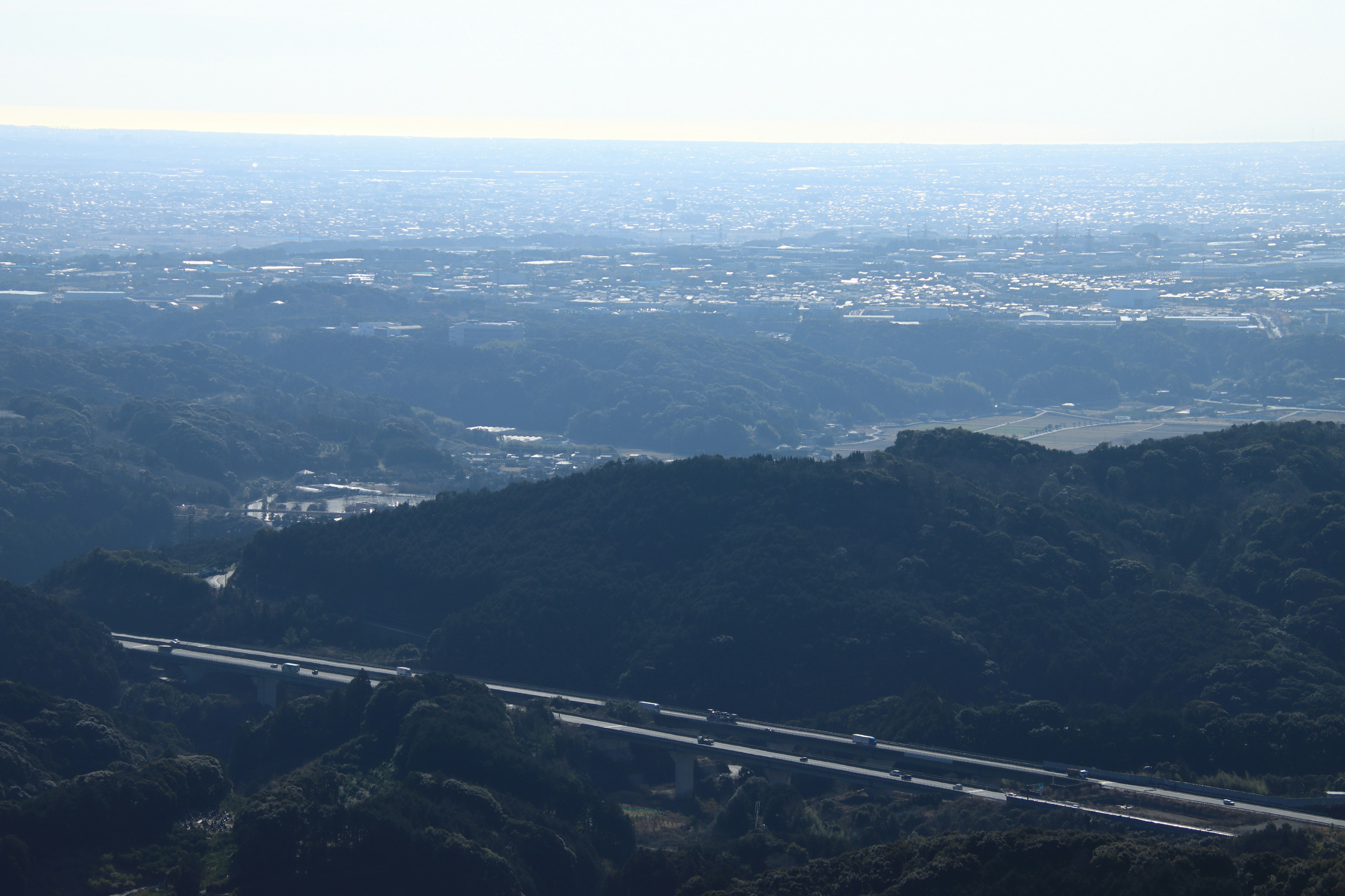 Luftaufnahme einer weiten Landschaft mit Autobahn und Bergen