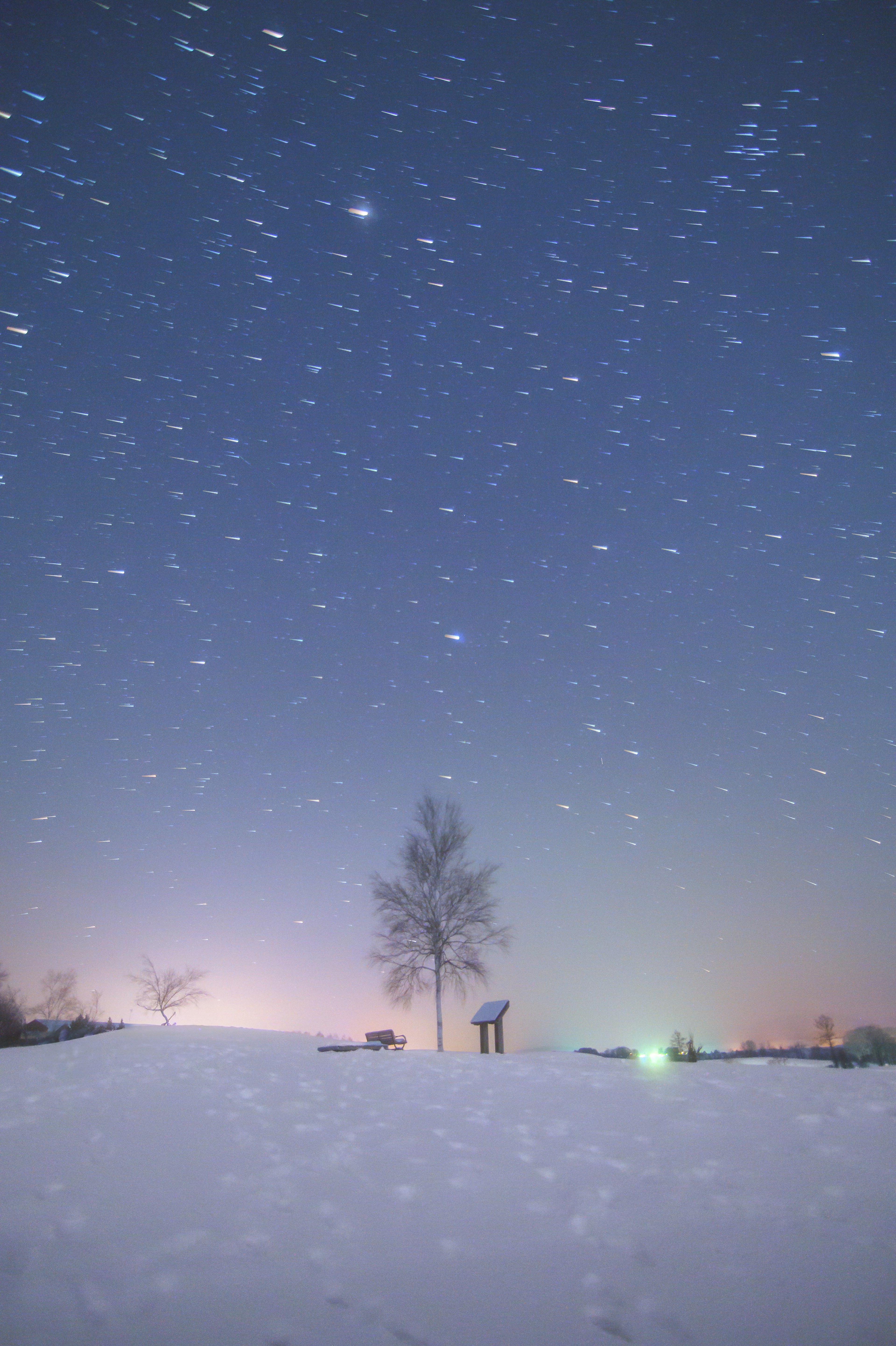 Paisaje nevado con un árbol y una persona bajo un cielo estrellado