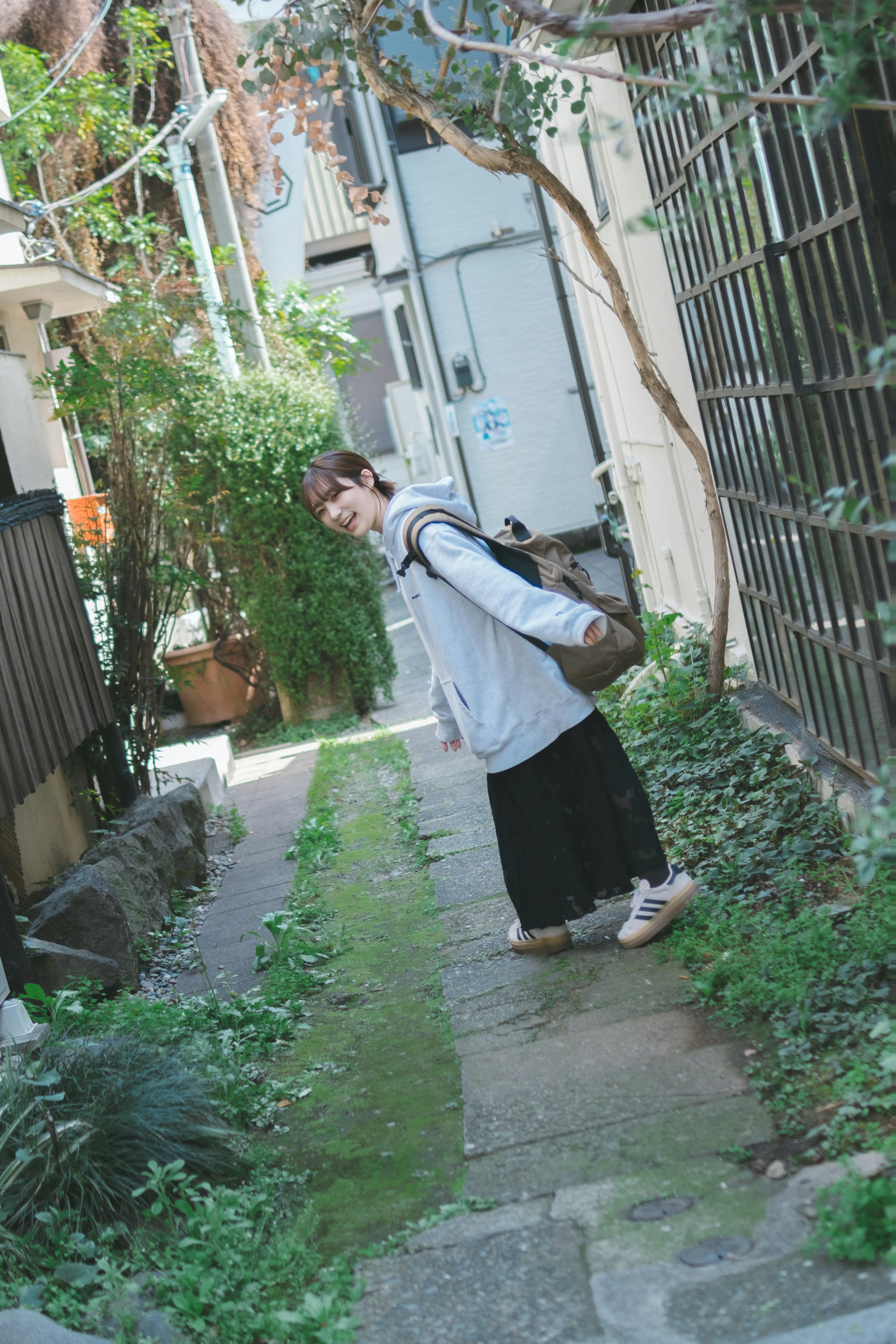 Femme marchant sur un chemin vert entouré de verdure dans une ruelle urbaine