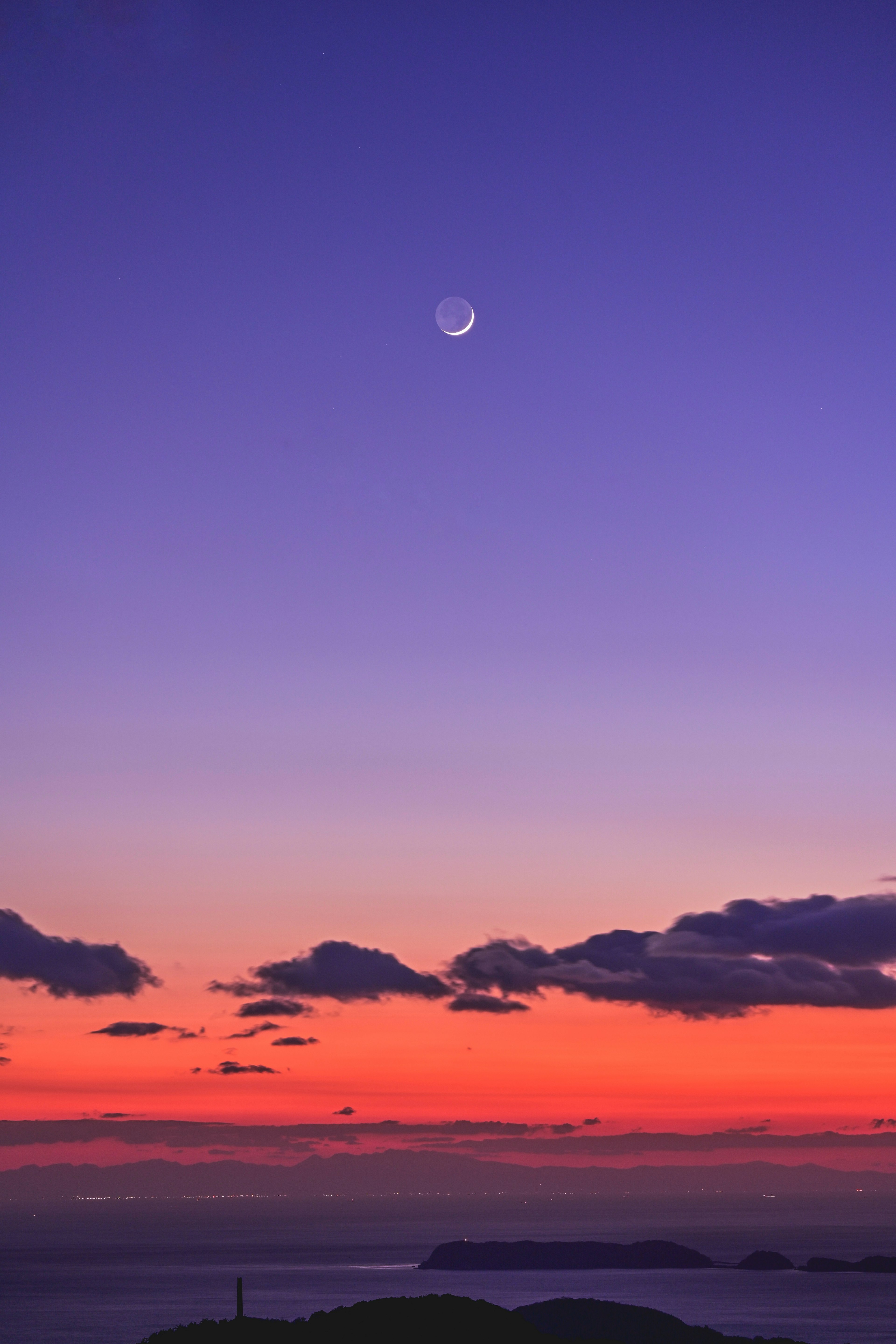 A stunning sunset with a crescent moon in the sky