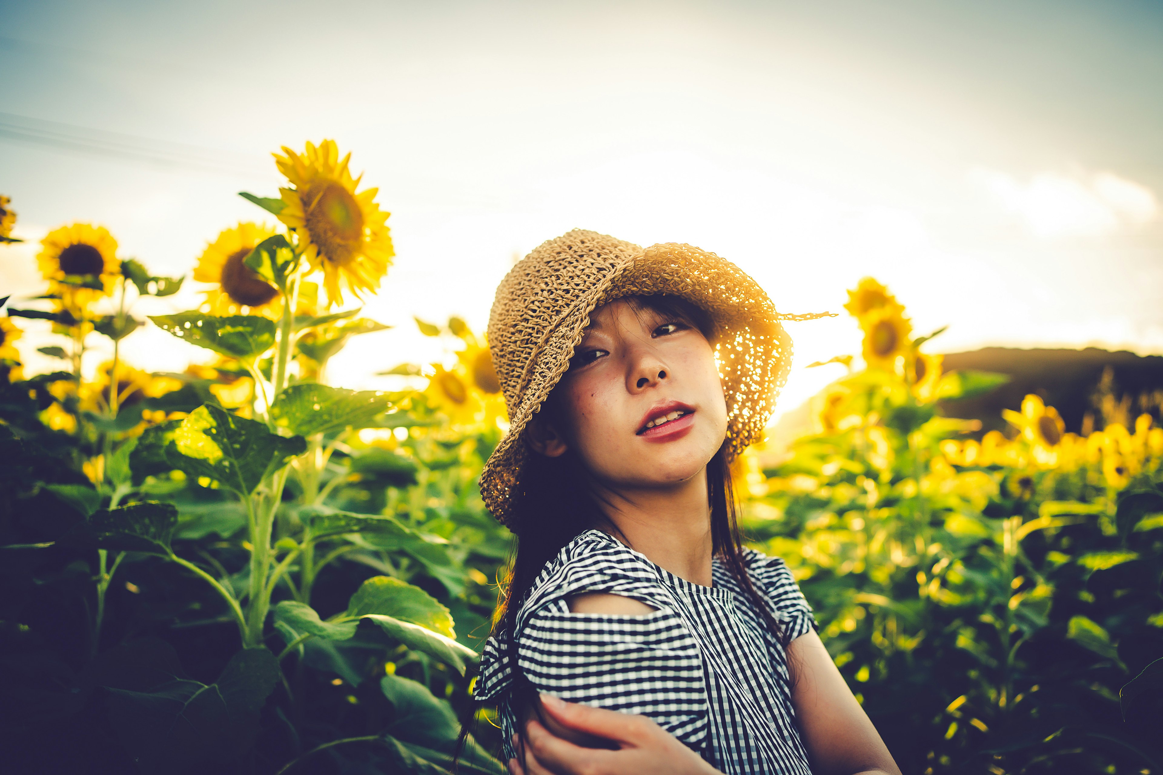 A girl in a straw hat posing in a sunflower field