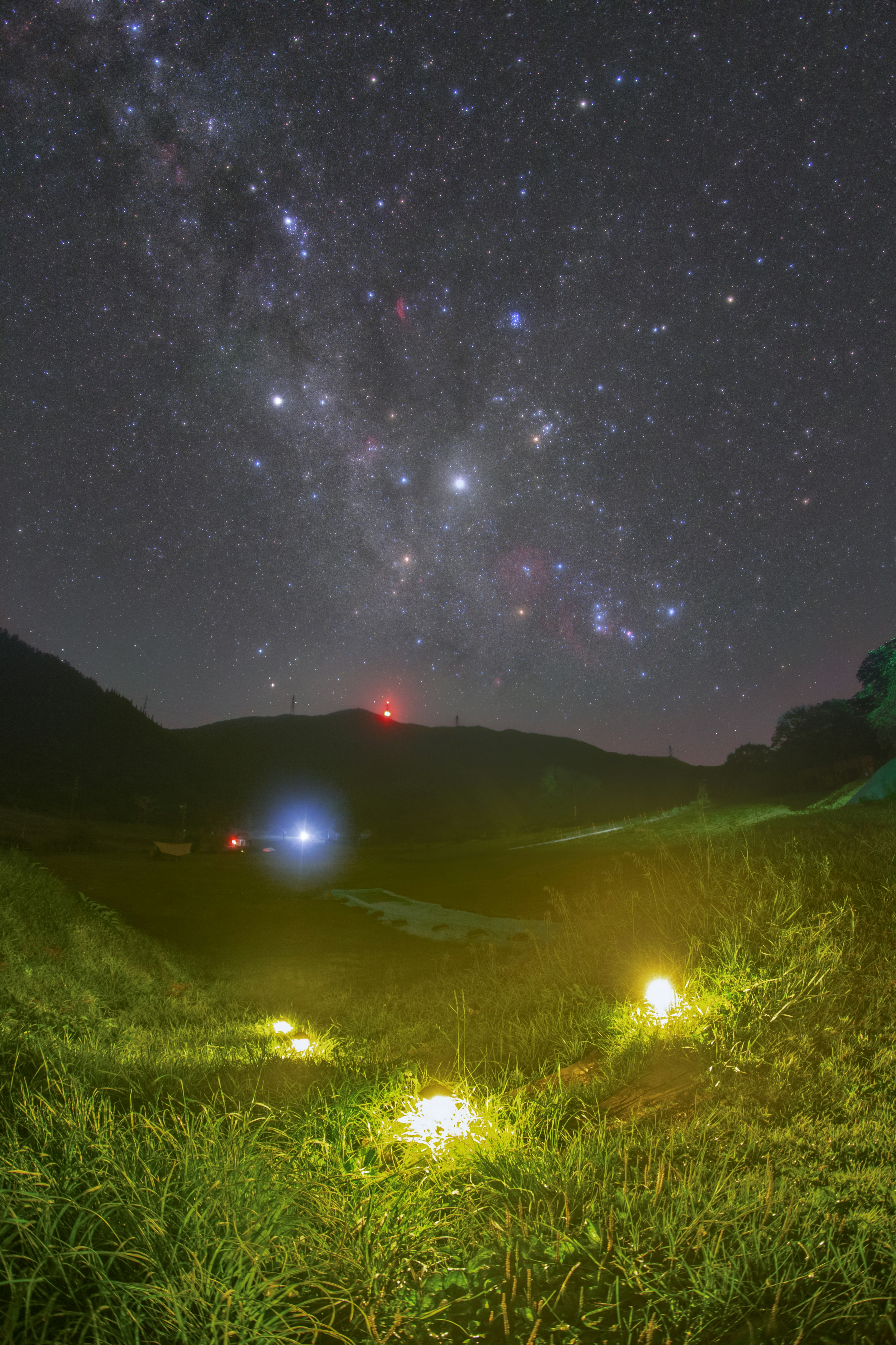 星空と草原の風景に輝く光源