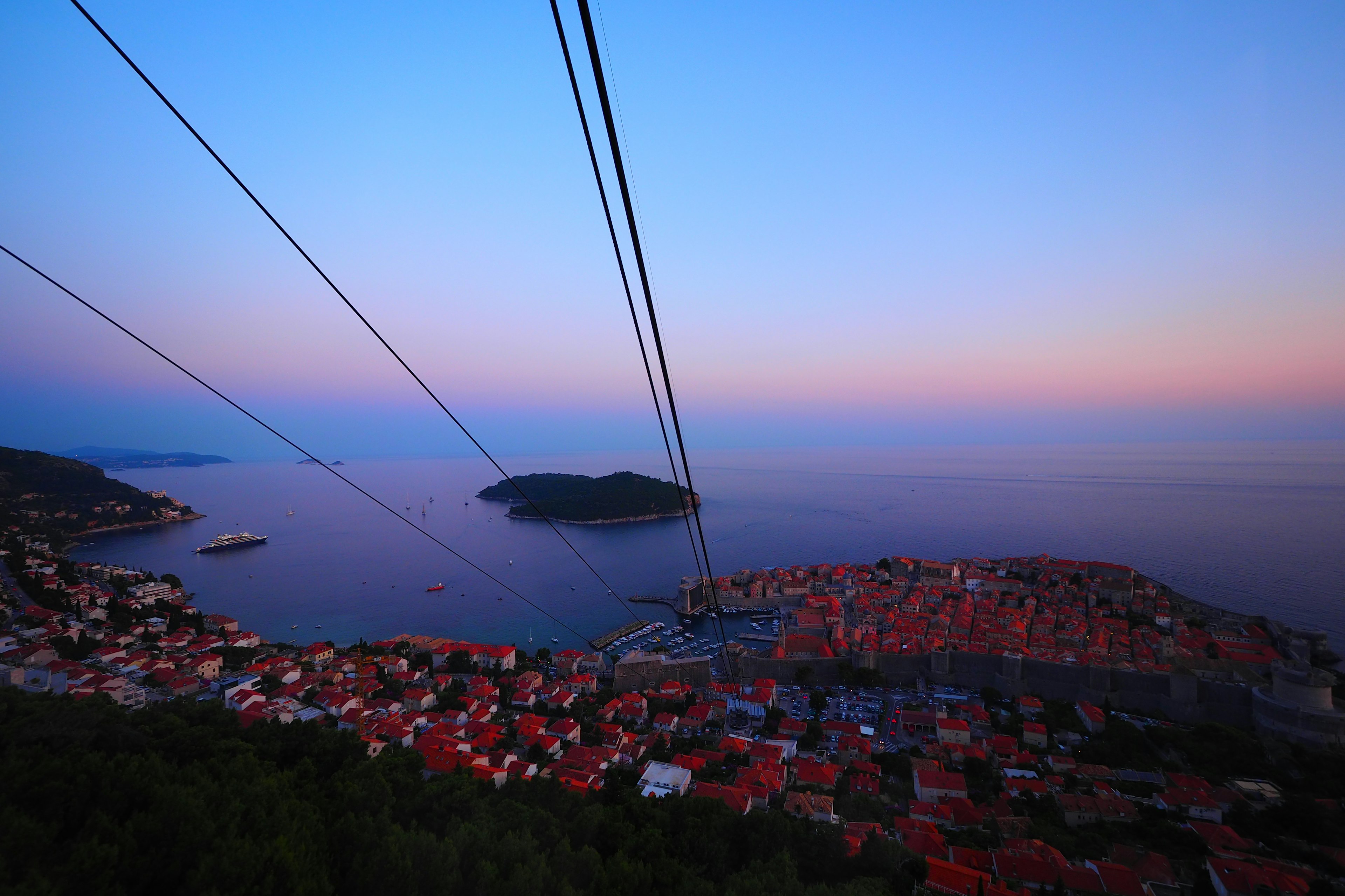 Vue magnifique du crépuscule sur la mer et l'île Câbles de téléphérique traversant le ciel